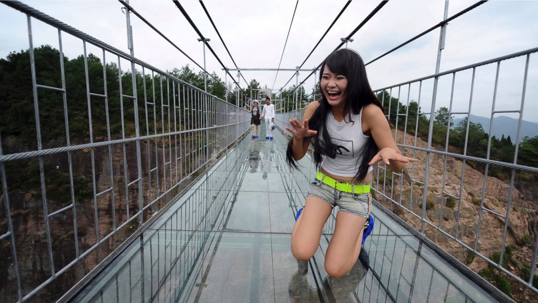 A visitor tries not to look down while crossing the glass walkway.