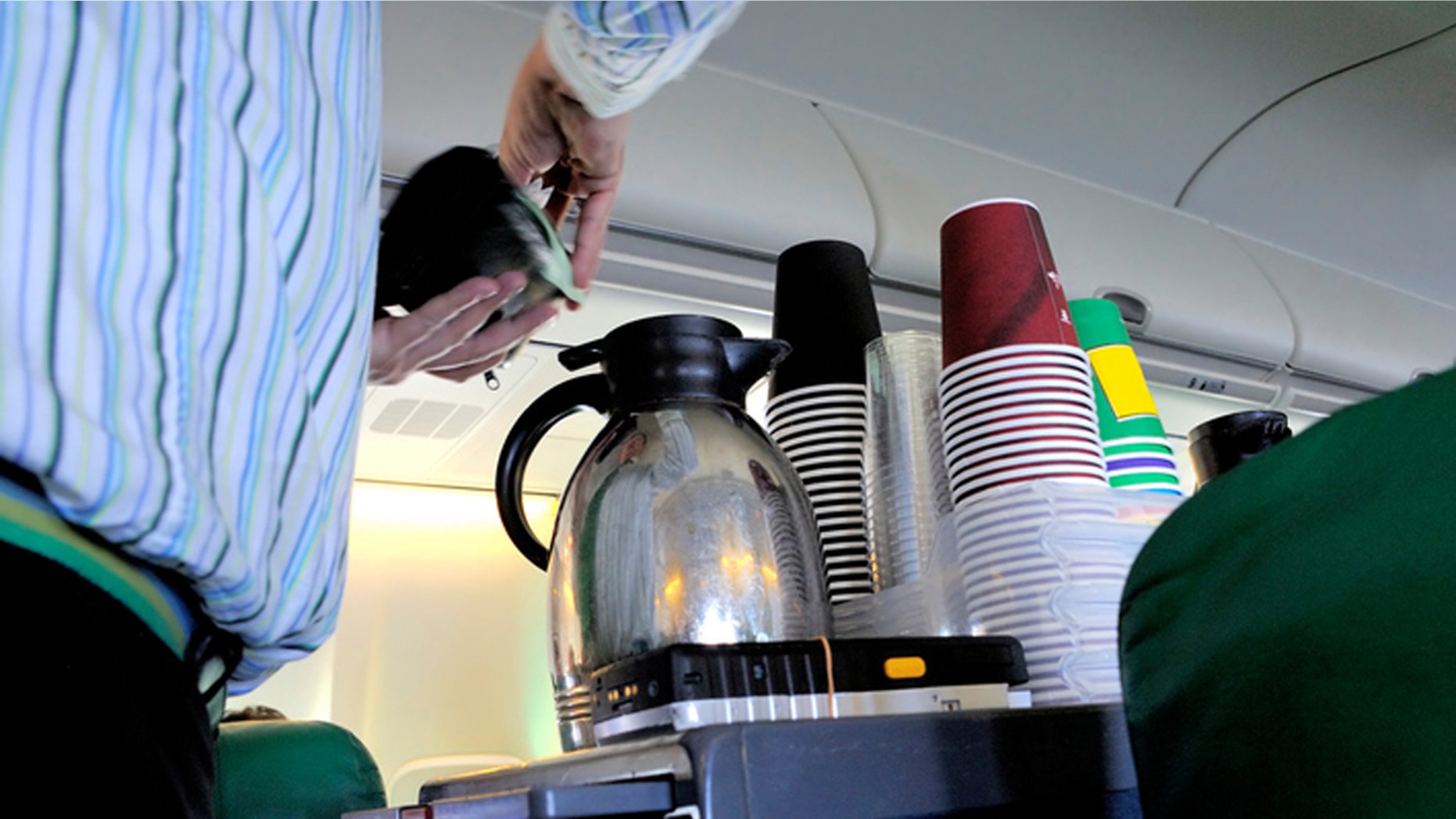 Steward pouring coffee in the cabin of an airplane