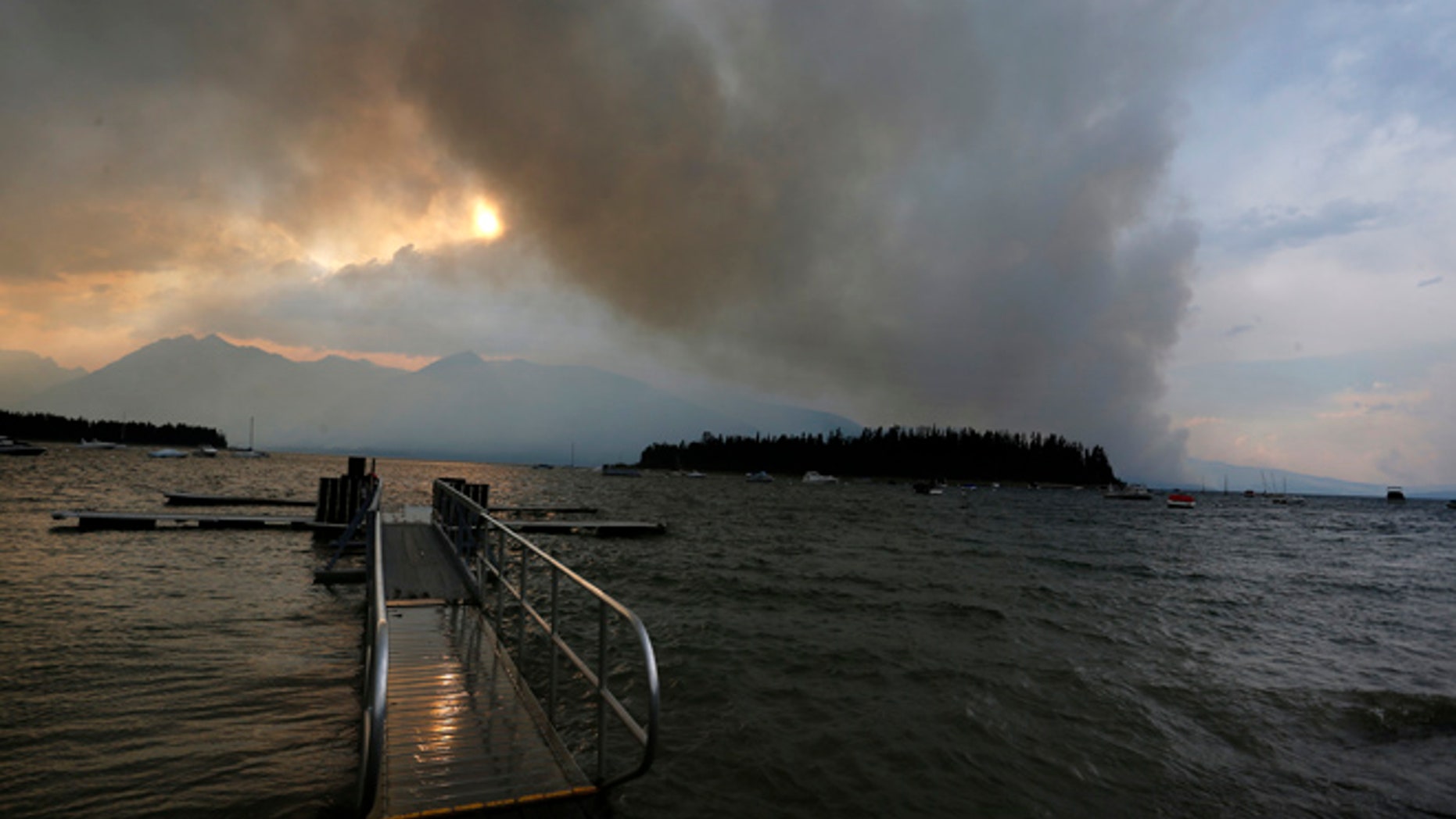 A wildfire is visible from Leek's Marina on the shore of Jackson Lake, in Grand Teton National Park, Wyo., Wednesday, Aug. 24, 2016.