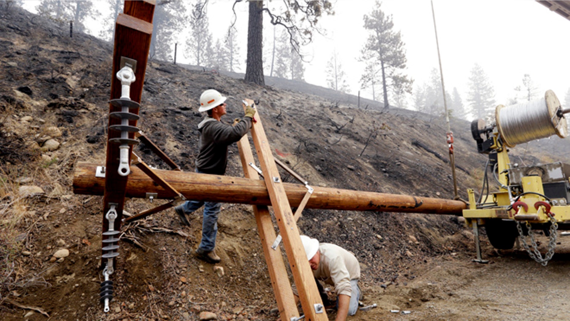 Aug. 23, 2015: Utility workers Chris Zahn, left, and Dan Foussard work to assemble a new pole to replace one of about 50 that burned down along Twisp River Road in a wildfire days earlier in Twisp, Wash.