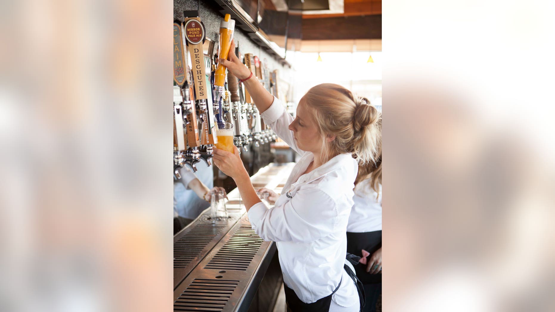 A server taps a pint of craft beer.