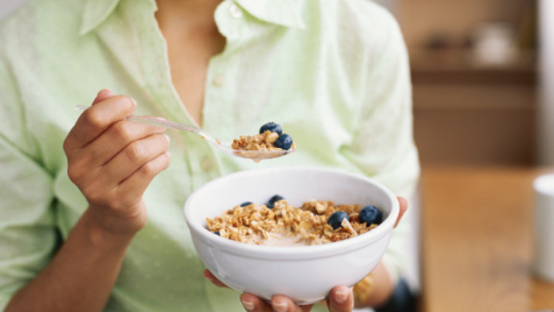 Woman holding bowl of cereal, mid section, close-up
