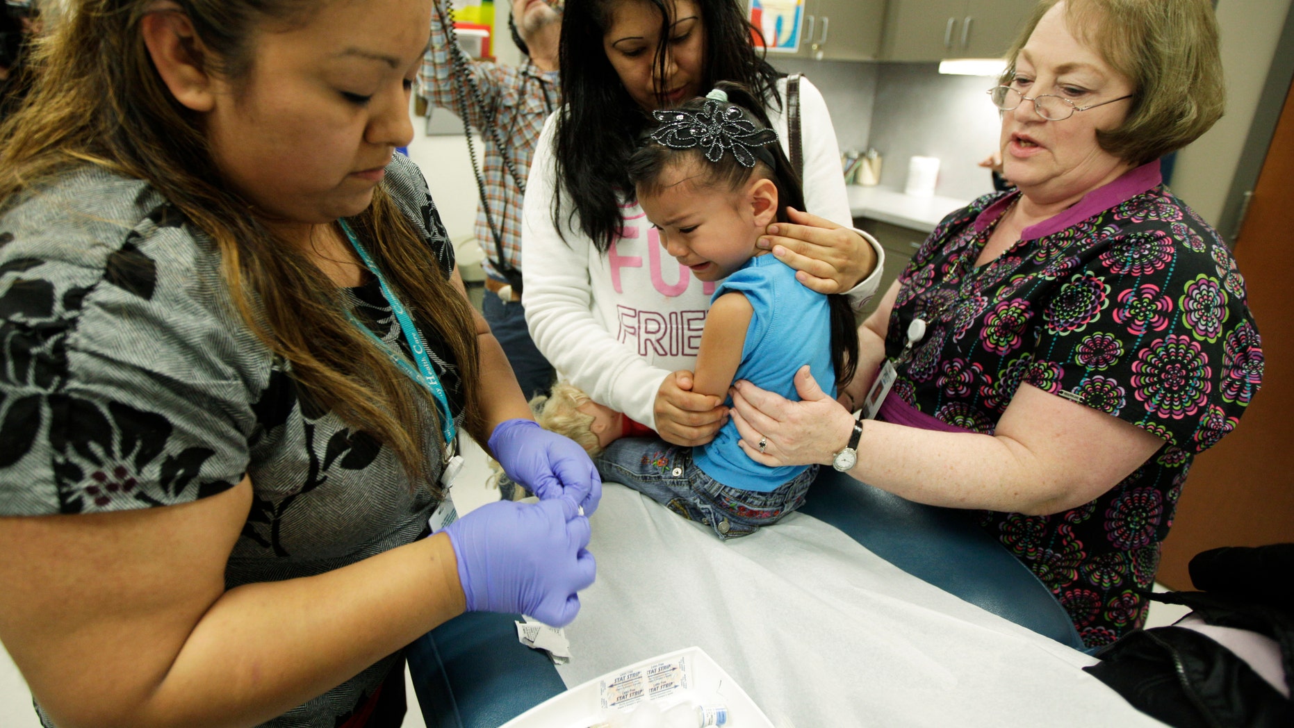 Nurses give a 4-year-old girl a Tdap whooping cough booster shot. (AP Photo/Ted S. Warren)
