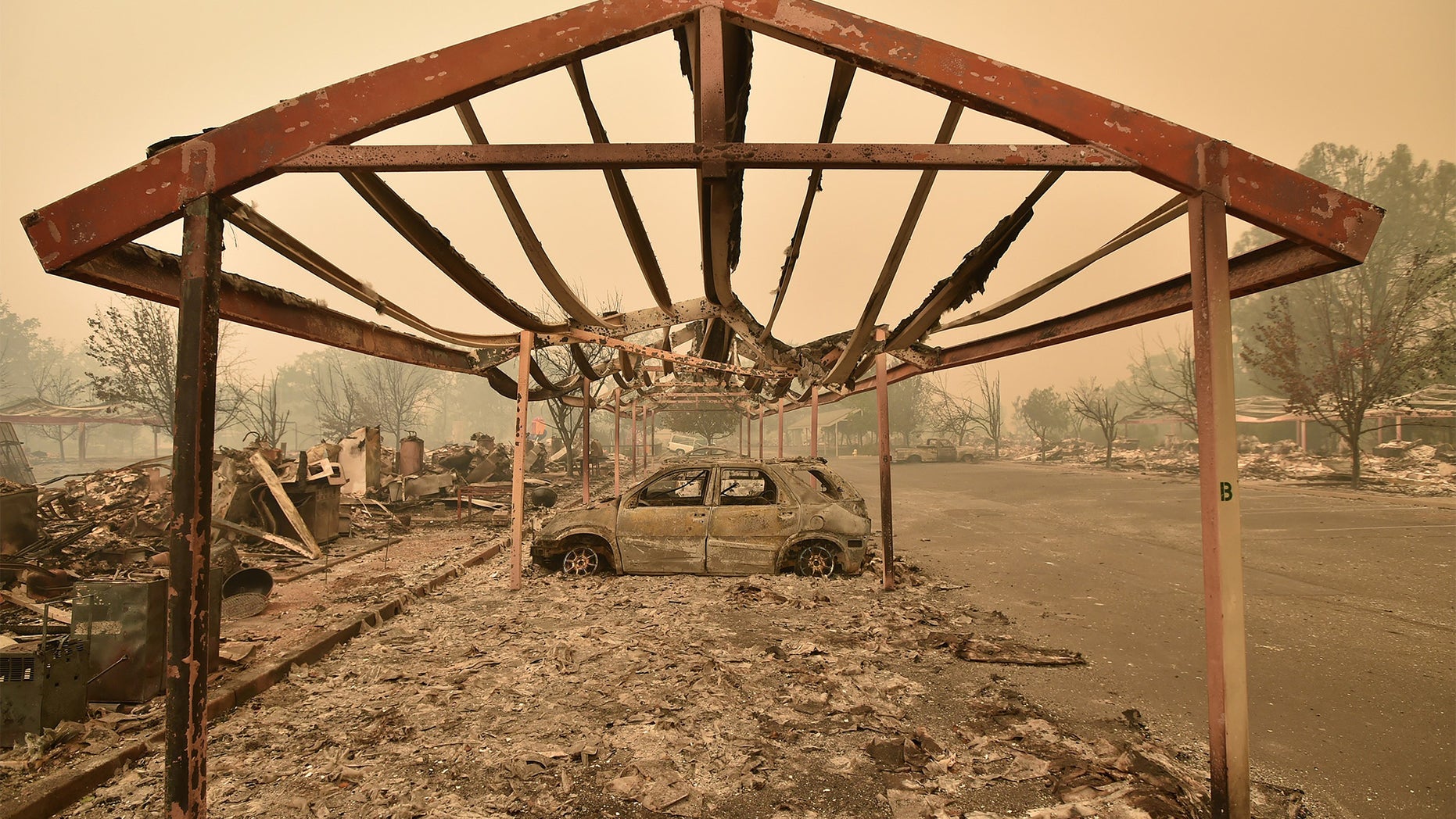 Burned out vehicles are surrounded by smoldering rubble while firefighters continue to battle the Valley fire in Middletown, California on September 13, 2015