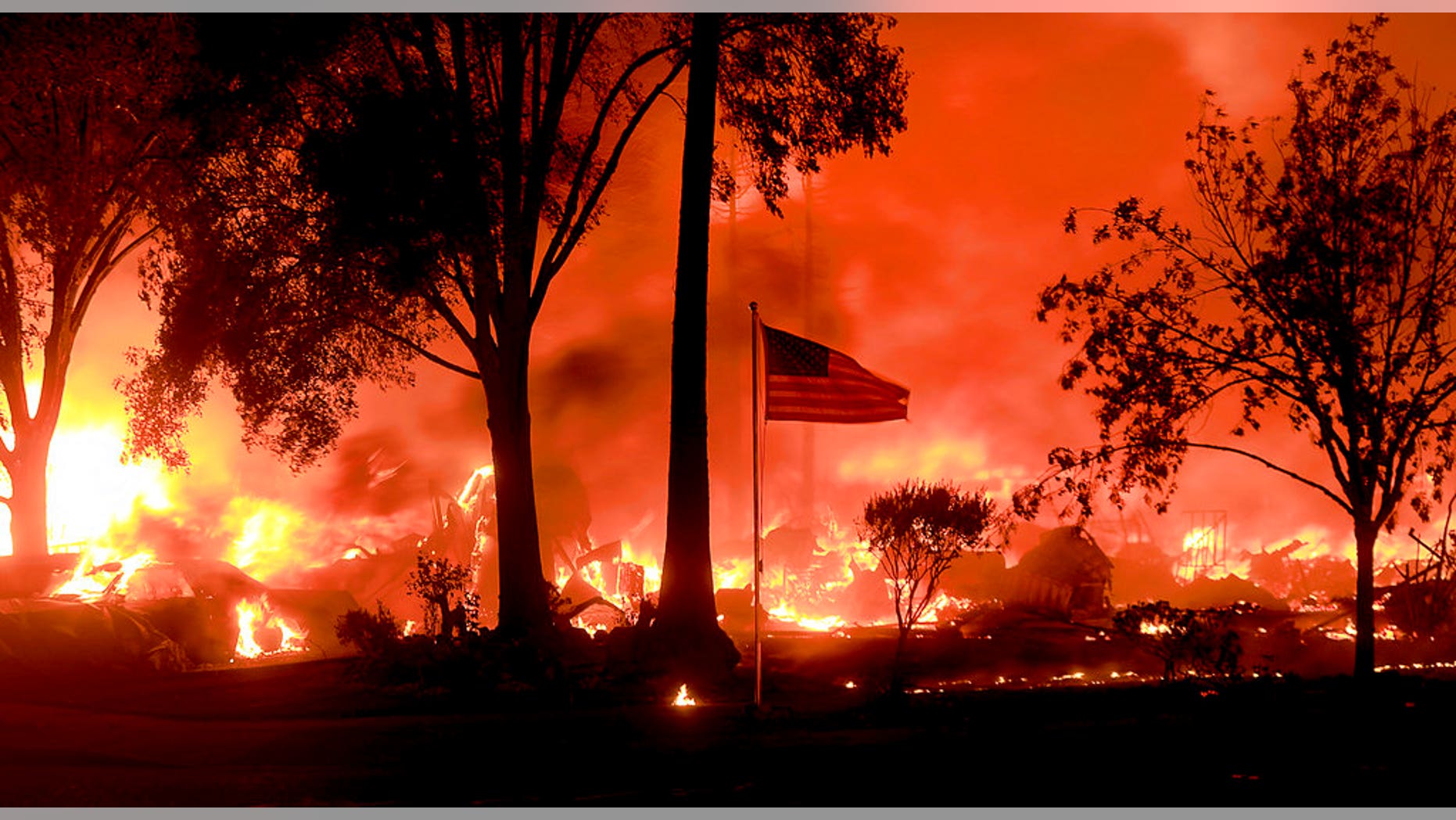An American flag still fly's as as structures burn in Coffey Park, Monday Oct. 9, 2017. More than a dozen wildfires whipped by powerful winds been burning though California wine country. The flames have destroyed at least 1,500 homes and businesses and sent thousands of people fleeing. (Kent Porter/The Press Democrat via AP)
