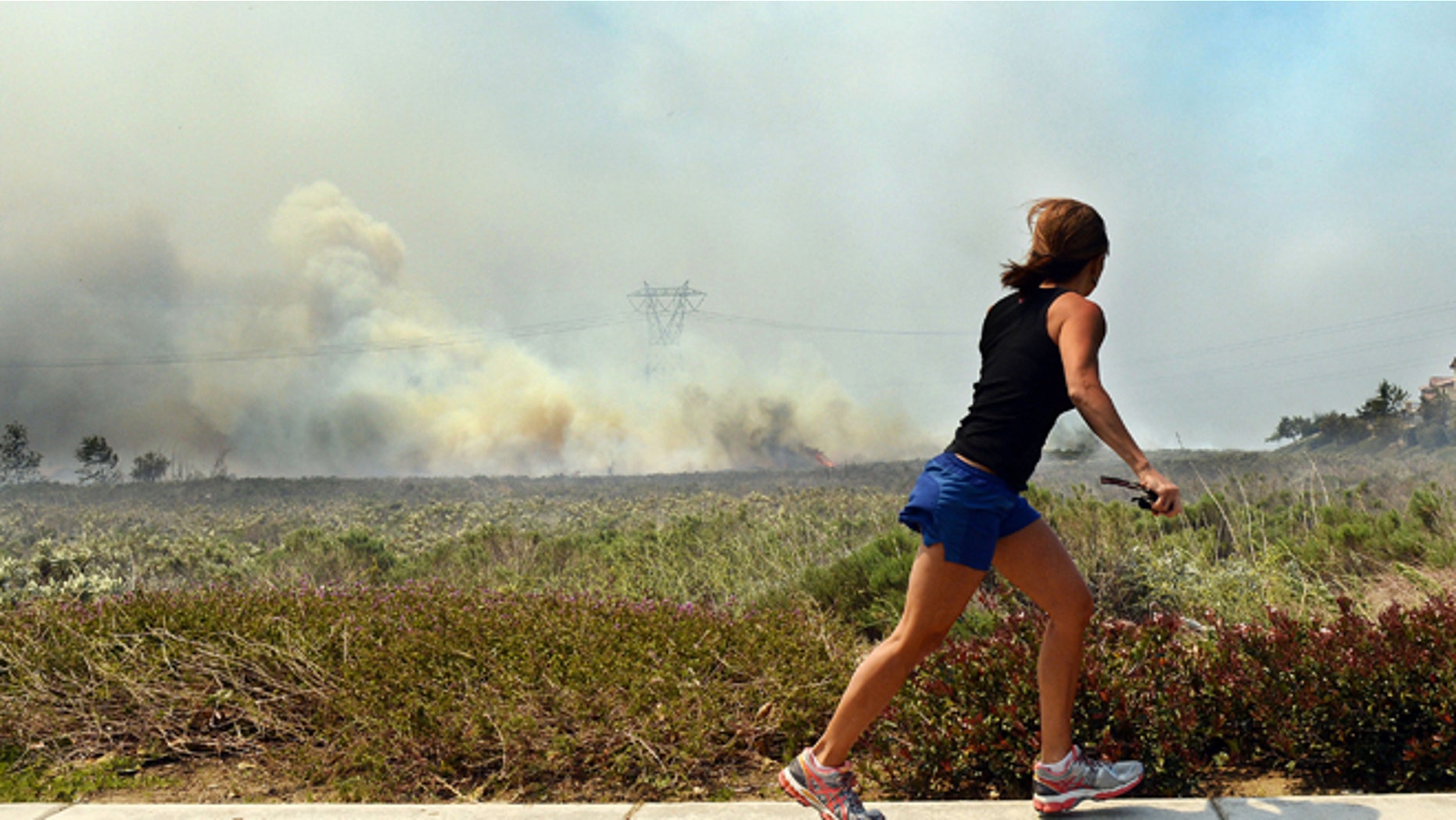 Apr. 30, 2014: A resident talks on her phone as she watches the Etiwanda Fire in Rancho Cucamonga, Calif.