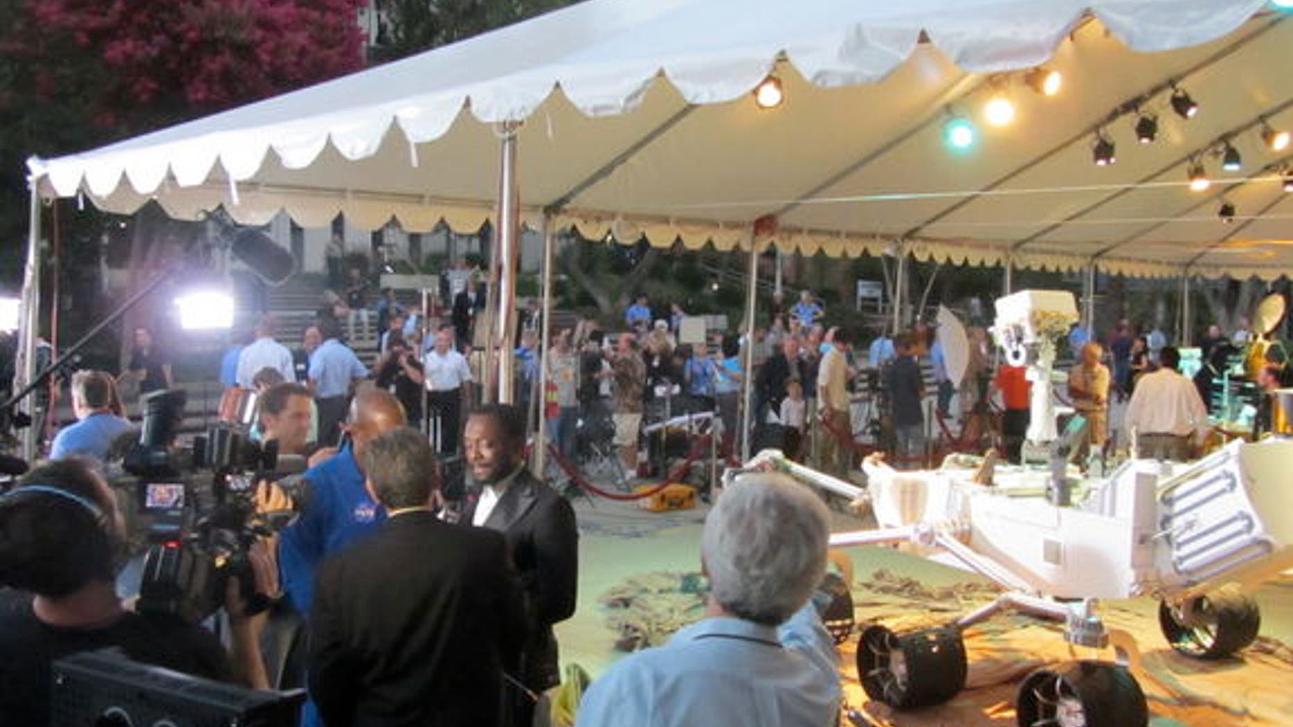 Musician will.i.am (center left) conducts an interview in front of a full-size model of the Curiosity rover on Aug. 5, 2012.