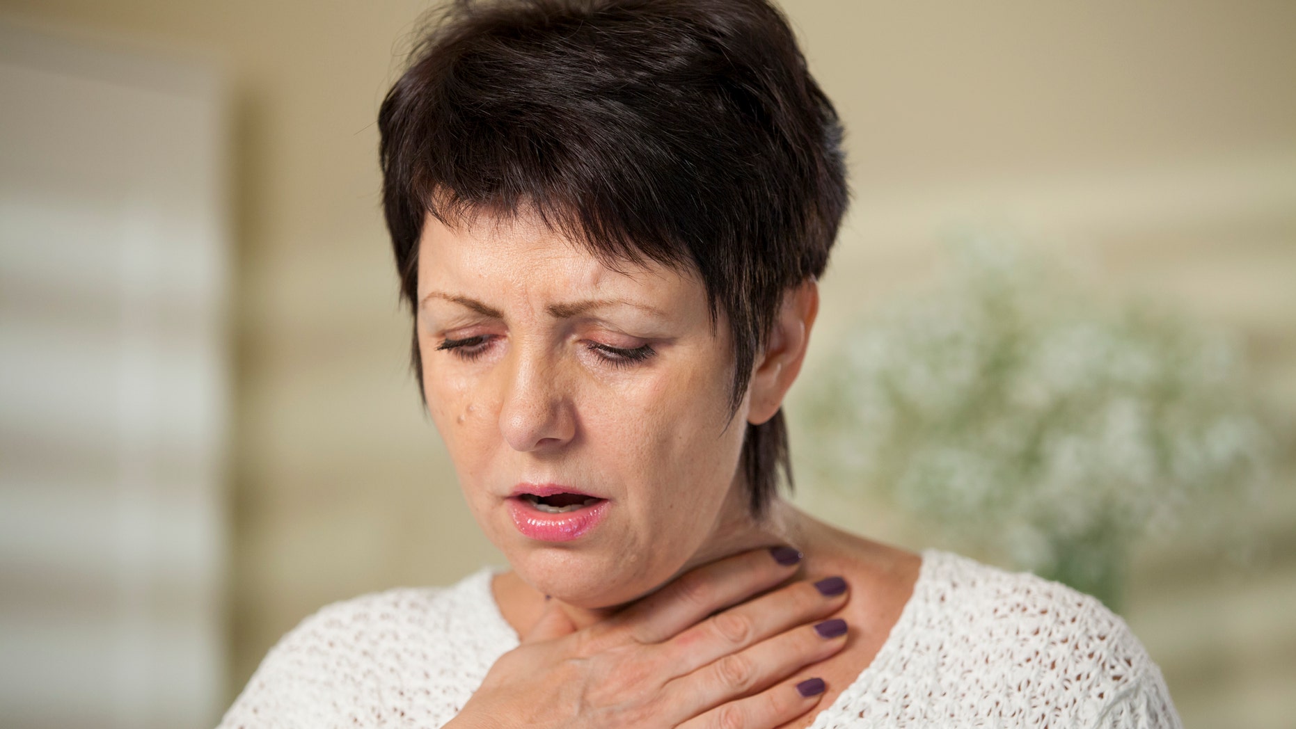 An unidentified woman suffers from a sore throat.