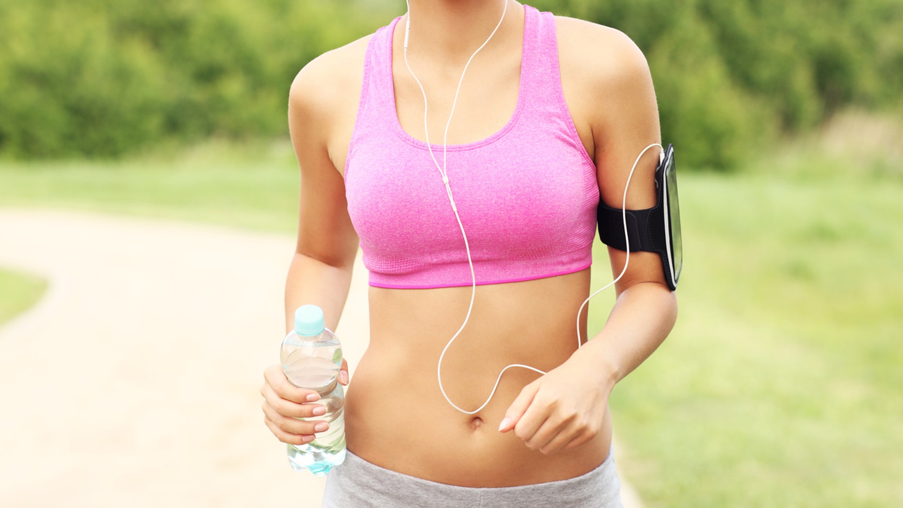 A picture of a woman jogging in the park with a bottle of water