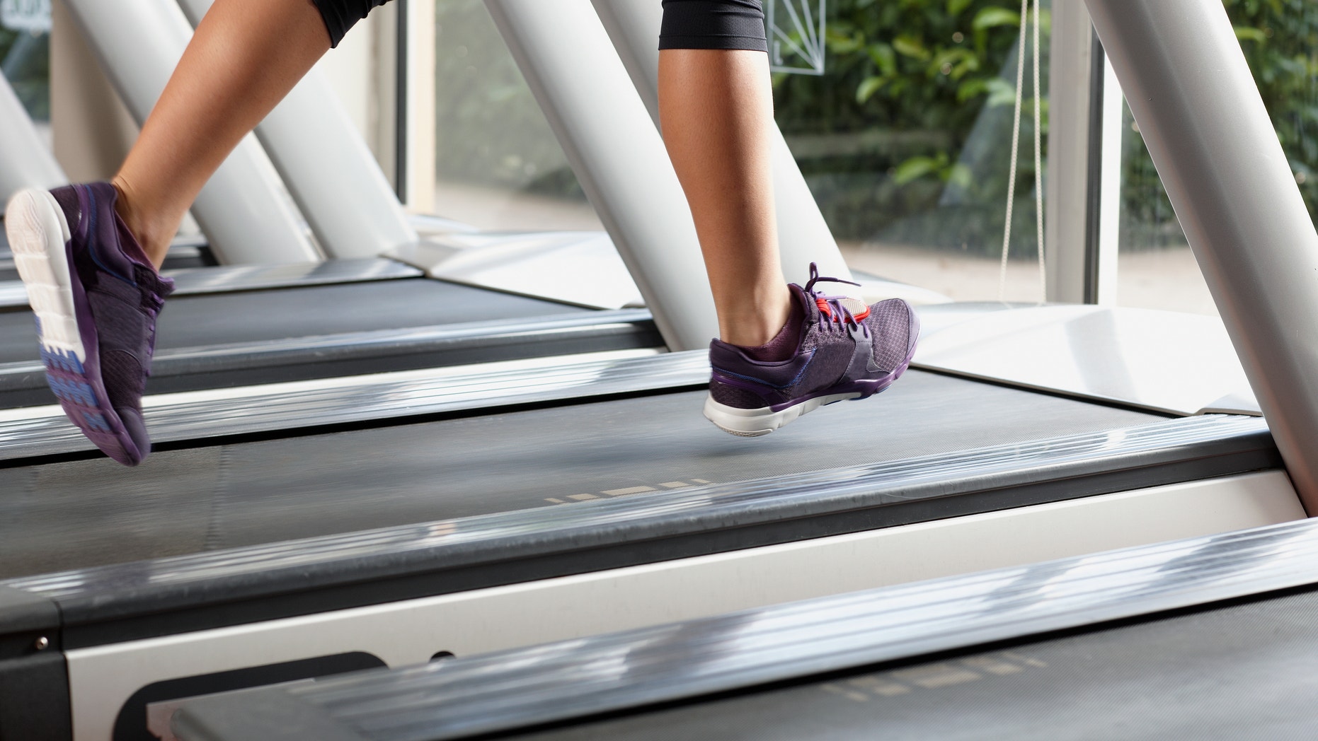 Close-up of woman's legs on treadmill. Some blurred parts due to movement.