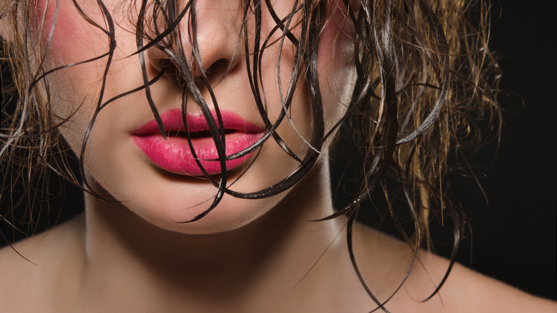 Portrait of beautiful woman with wet hair on dark background