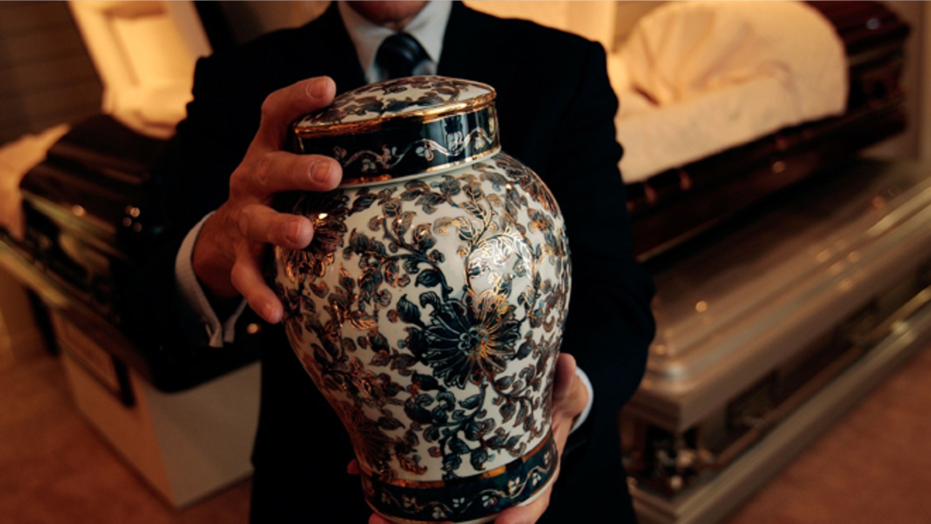 NEW YORK - NOVEMBER 20: Funeral director Peter DeLuca, owner of Greenwich Village Funeral Home, holds a cremation urn in the showroom of his funeral parlor on November 20, 2008 in New York City. New technologies, such as flat screen televisions for video memorials, ornate and even sports-team themed cremation urns are also slowly being introduced at funeral homes. Despite the currently languishing economy, the funeral home world is readying for an upswing nationally, as the recession-resistant business prepares for an expected rise in death rates as baby boomers start to reach old age in the coming decade. (Photo by Chris Hondros/Getty Images)