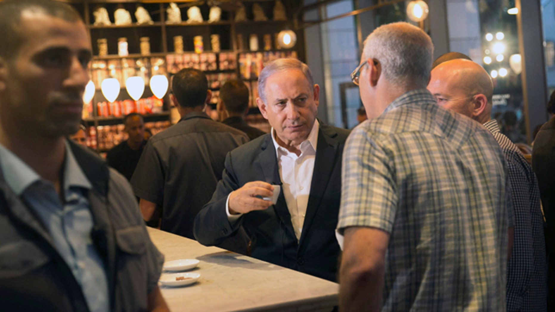 Israeli Prime Minister Benjamin Netanyahu sits at the scene of Wednesday's shooting attack at a Tel Aviv restaurant, Thursday, June 9, 2016. Israel on Thursday imposed travel restrictions on tens of thousands of Palestinians and sent hundreds of additional troops into the West Bank in response to a deadly shooting at a popular Tel Aviv tourist spot, but as the nation's leaders vowed tough responses, they stopped short of taking wider scale military action. (AP Photo/Tomer Appelbaum) ISRAEL OUT