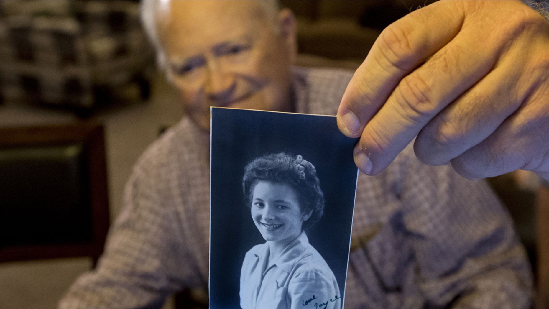 FILE - In this Nov. 6, 2015 file photo, Norwood Thomas, holds up a photo of with Joyce Morris at his home in Virginia Beach, Va. Thomas arrived in Australia Wednesday to reunite with Morris, his girlfriend during World War II. (Bill Tiernan/The Virginian-Pilot via AP)
