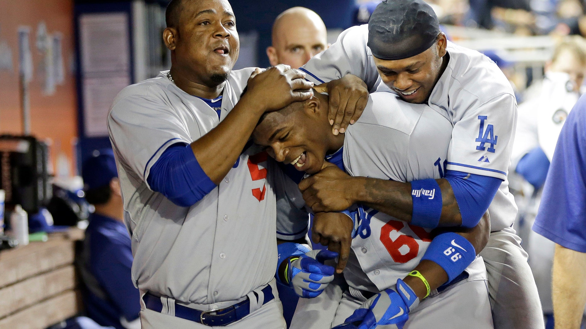 Los Angeles Dodgers' Yasiel Puig, center, is congratulated in the dugout by teammates Juan Uribe, left, and Hanley Ramirez, right, after hitting a home run in the eighth inning during a baseball game against the Miami Marlins, Tuesday, Aug. 20, 2013 in Miami. The Dodgers won 6-4.(AP Photo/Lynne Sladky)