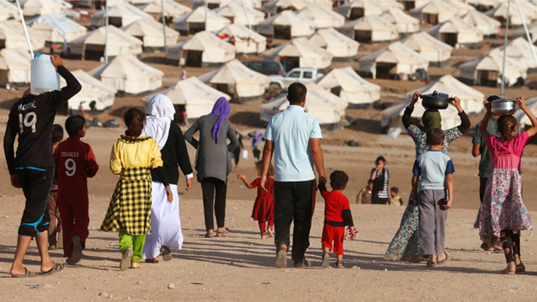 Aug. 22, 2014: Displaced people from the minority Yazidi sect, who fled violence in the Iraqi town of Sinjar, walk in Bajed Kadal refugee camp south west of Dohuk province