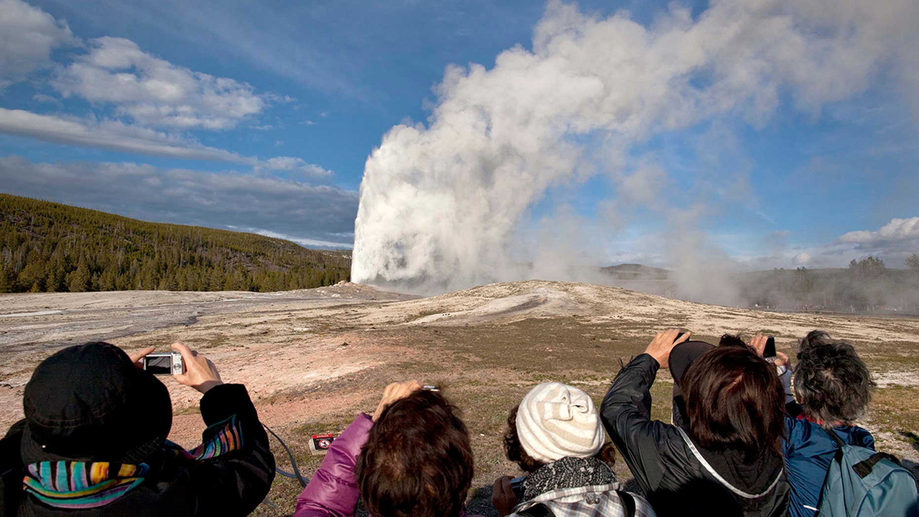In this May 21, 2011, file photo, tourists photograph Old Faithful erupting on schedule late in the afternoon in Yellowstone National Park, Wyo.