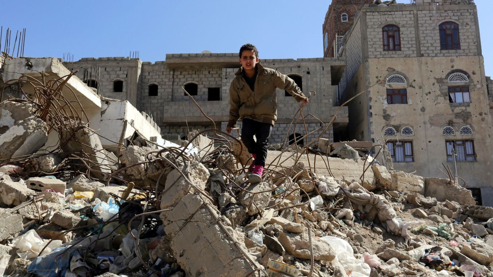 Sana'a. A child stands in the middle of destroyed buildings in his neighborhood.