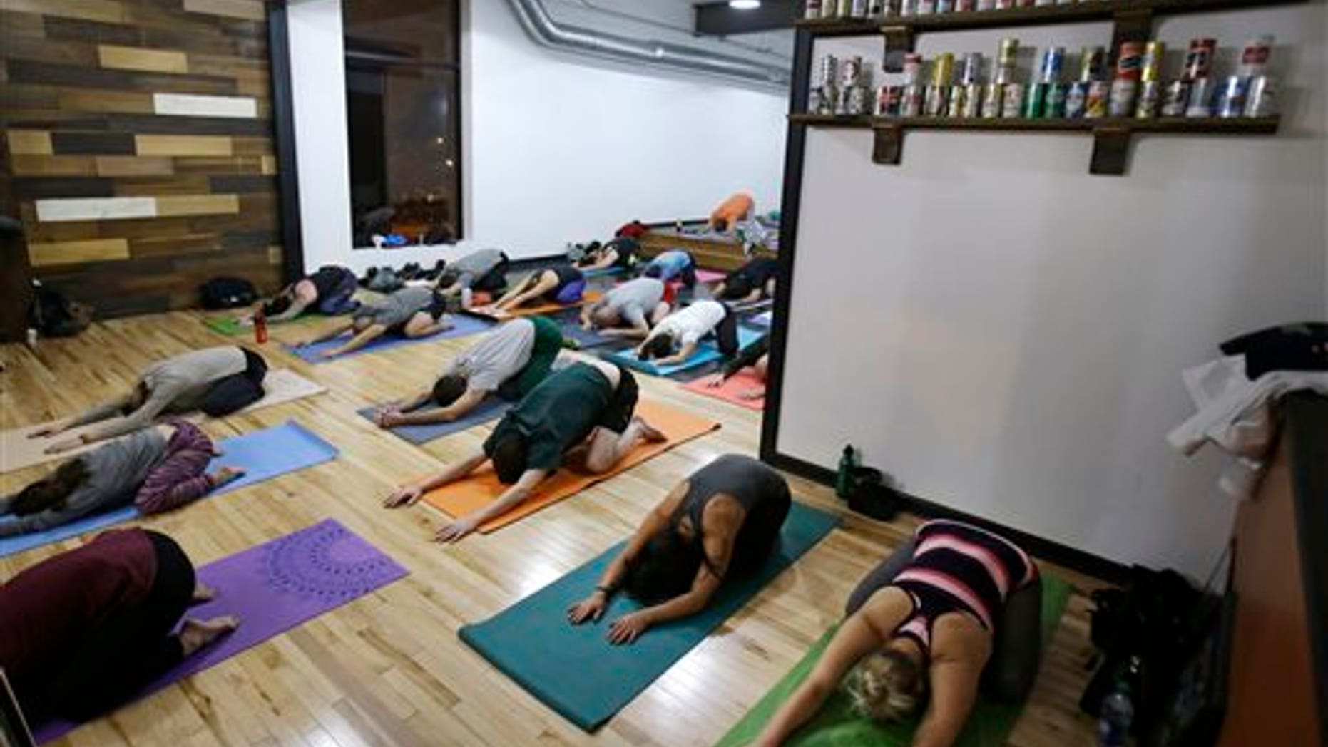 This Thursday, Dec. 3, 2015 photo shows participants practicing yoga at the Platform Beer Co., in Cleveland. Craft breweries are partnering up with yoga studios around the country as more breweries are hosting classes to attract a new crowd to the bars and yoga studios are using the beer to get more men to try yoga. (AP Photo/Tony Dejak)
