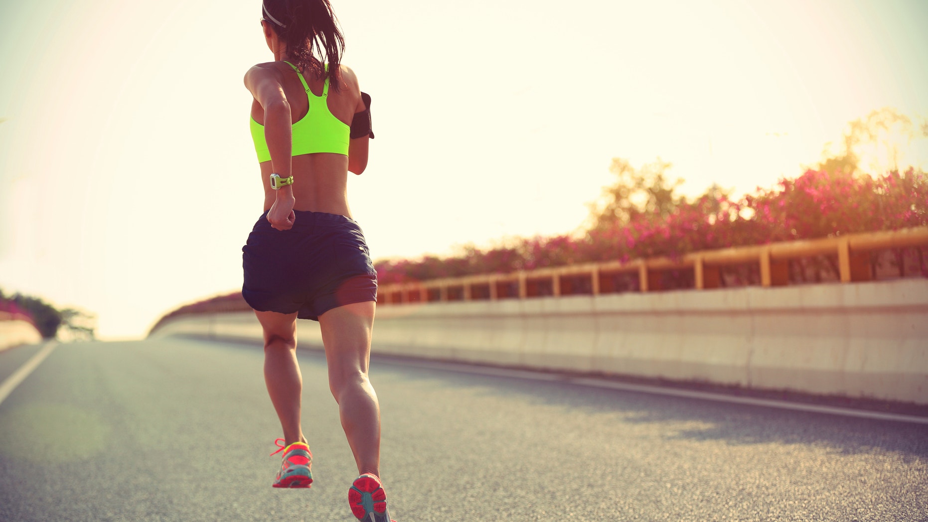 young woman runner running on city bridge road