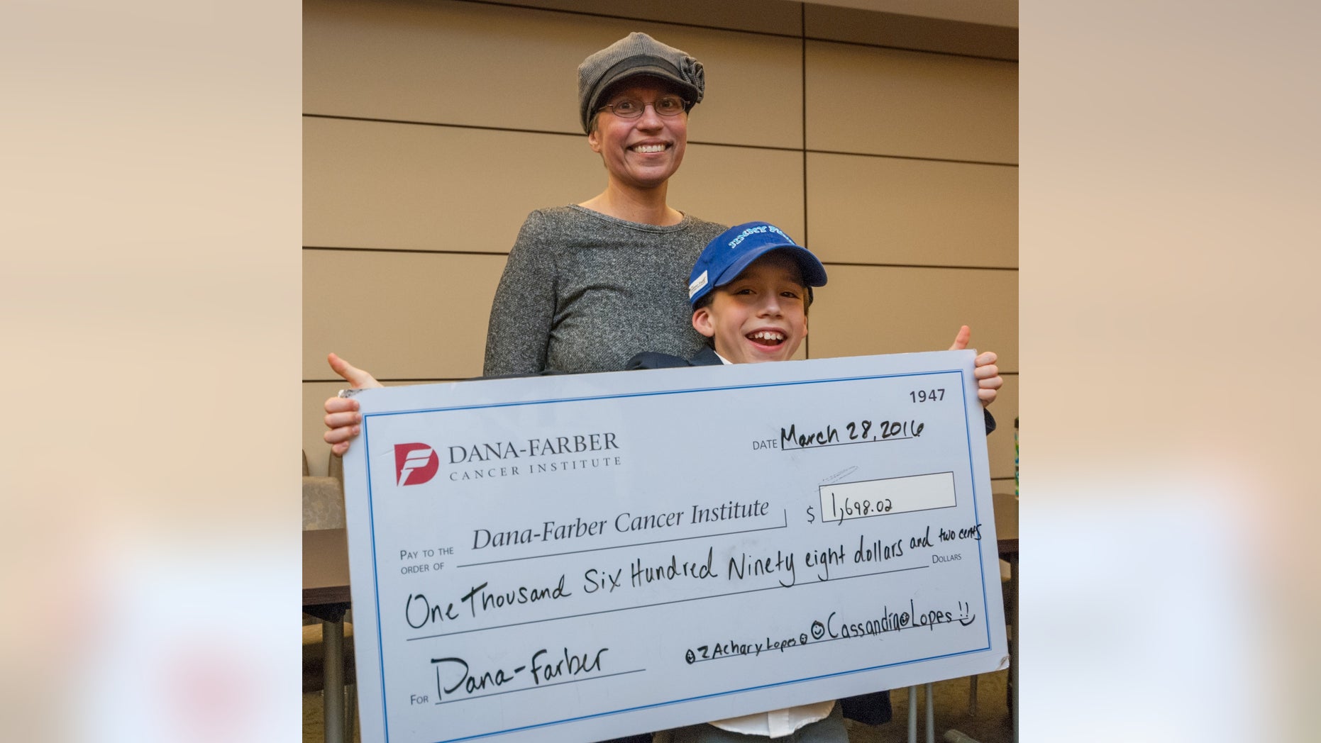 Zach Lopes and his mother, Christine, pose for a photo with the check Zach presented to the Dana-Farber Cancer Institute.