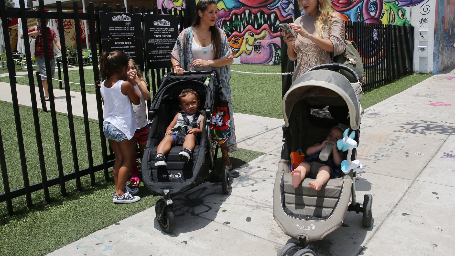 Vanessa Gomez, 33, left, with her son Ezra, 2, and her friend Cristy Fernandez, 33, with her 9-month-old- son River, of Miami, walk in the Wynwood neighborhood of Miami, Friday, July 29, 2016. Florida health officials said that four patients in Florida infected with the Zika virus were infected in the Wynwood area. These cases are believed to have caught the virus locally through mosquito bites. Gomez said the news is "scary but we cannot stop living our lives." To the left are Olivia Gomez, 5, and Kaly Fernandez. (AP Photo/Marta Lavandier)