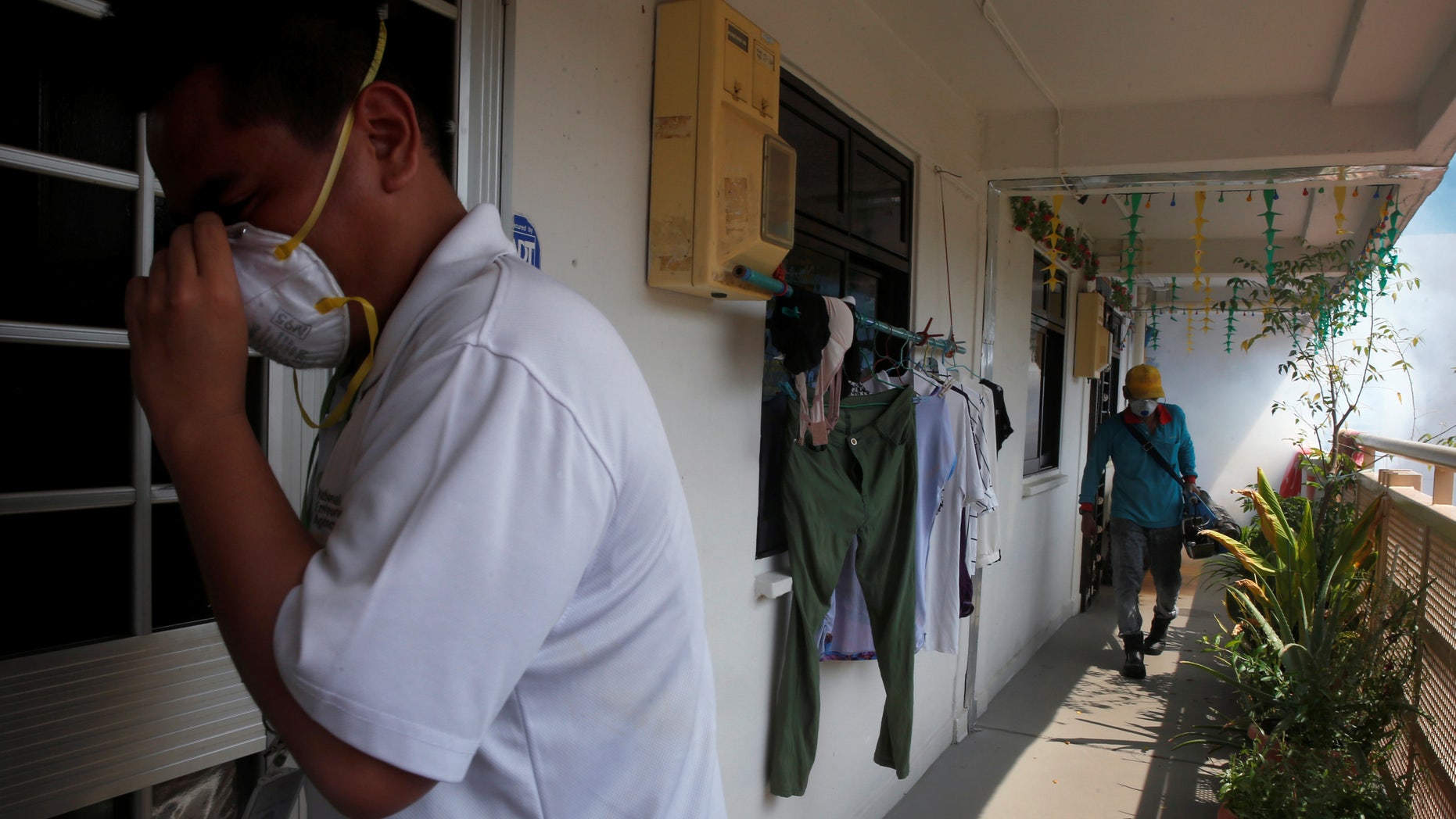 A National Environment Agency officer informs residents as a worker fogs the corridor of a public housing estate in the vicinity where a locally transmitted Zika virus case was discovered, in Singapore August 29, 2016.