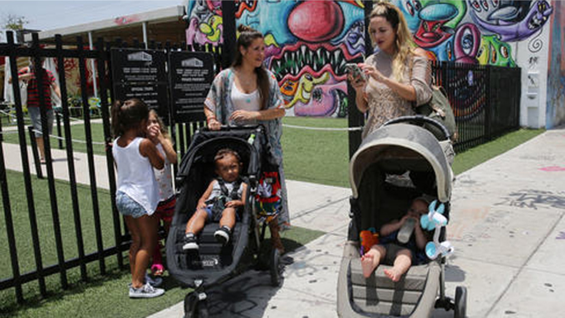Vanessa Gomez, 33, left, with her son Ezra, 2, and her friend Cristy Fernandez, 33, with her 9-month-old- son River, of Miami, walk in the Wynwood neighborhood of Miami, Friday, July 29, 2016. Florida health officials said that four patients in Florida infected with the Zika virus were infected in the Wynwood area. These cases are believed to have caught the virus locally through mosquito bites. Gomez said the news is "scary but we cannot stop living our lives." To the left are Olivia Gomez, 5, and Kaly Fernandez. (AP Photo/Marta Lavandier)