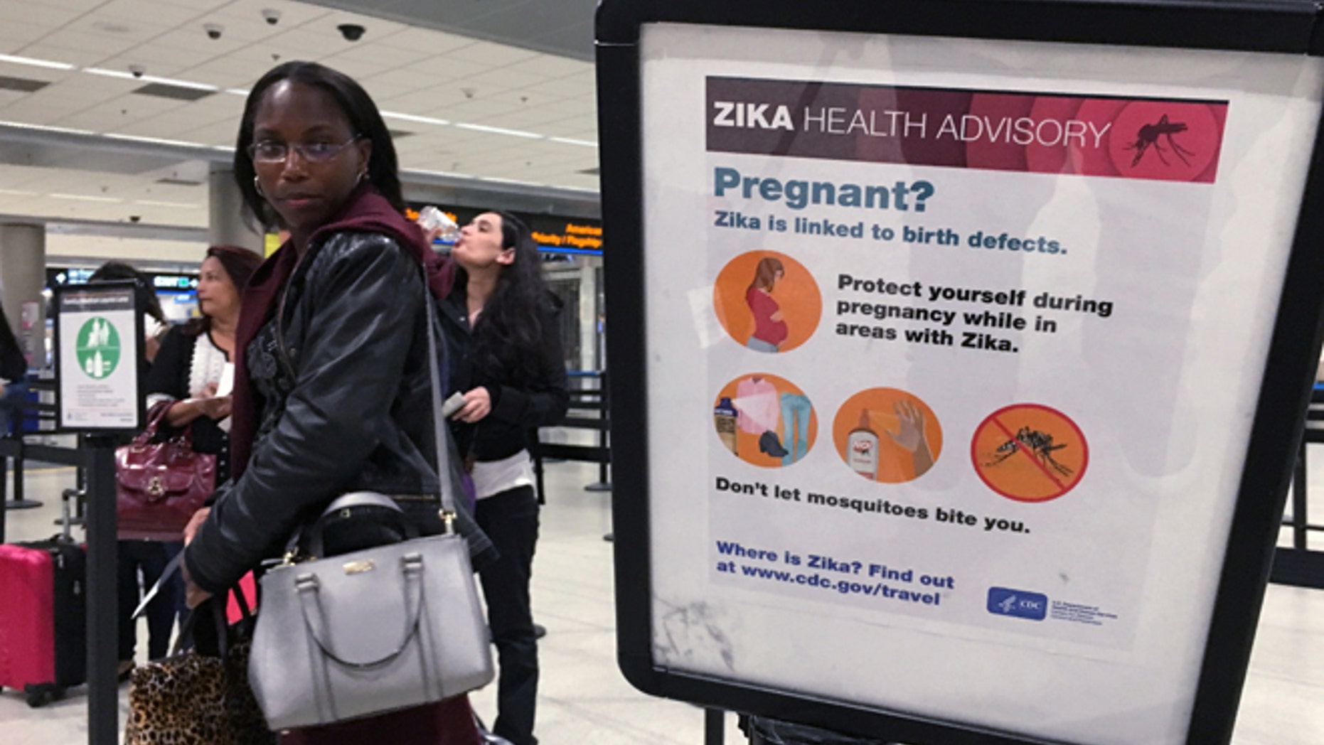 May 23, 2016: A woman looks at a Center for Disease Control (CDC) health advisory sign about the dangers of the Zika virus as she lines up for a security screening at Miami International Airport in Miami, Florida, U.S.