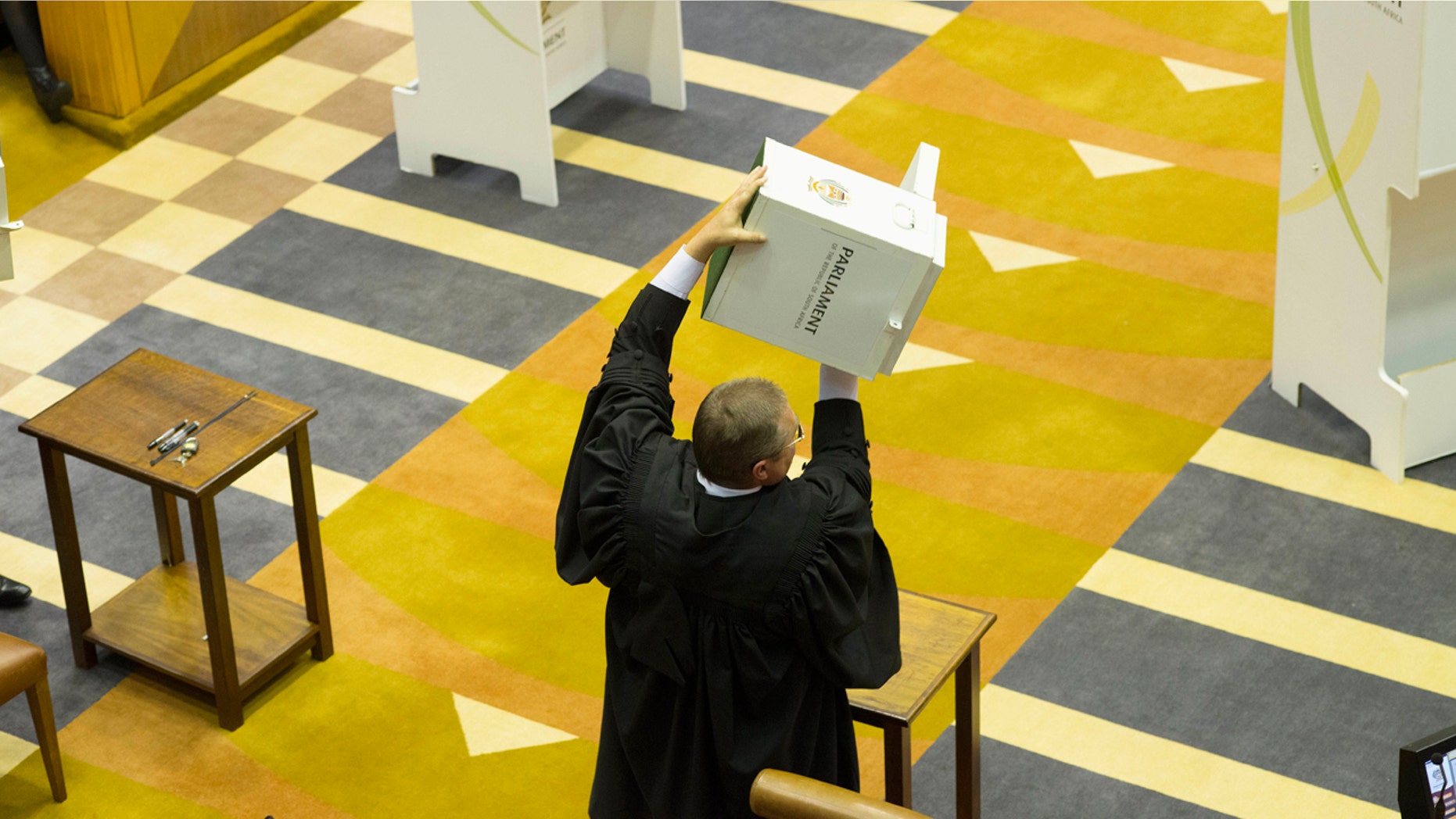 A parliamentary officer shows an empty ballot box to the South African parliament before voting for or against the motion of no confidence against South African president, Jacob Zuma in the South African parliament in Cape Town, South Africa, Tuesday, Aug. 8, 2017.