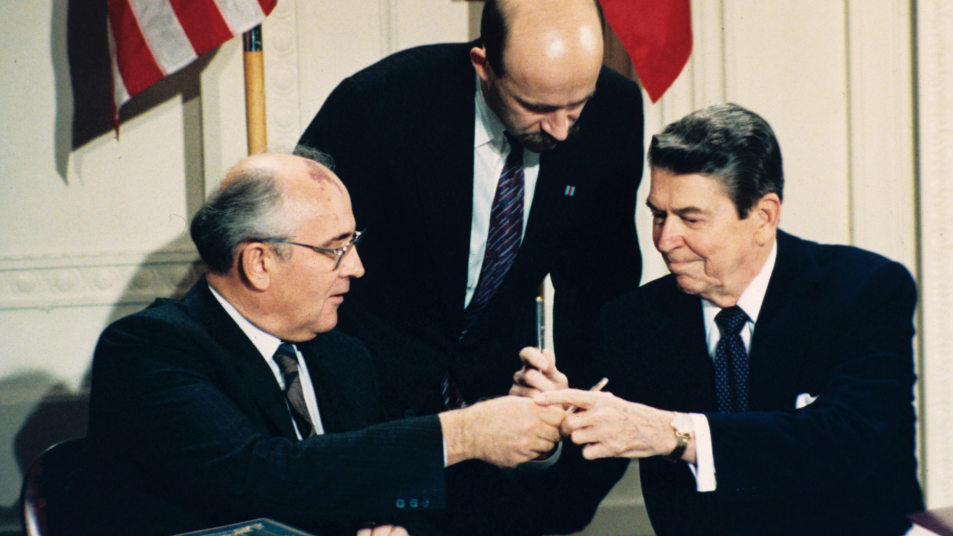 FILE - In this Dec. 8, 1987 file photo U.S. President Ronald Reagan, right, and Soviet leader Mikhail Gorbachev exchange pens during the Intermediate Range Nuclear Forces Treaty signing ceremony in the White House East Room in Washington, D.C. Gorbachev's translator Pavel Palazhchenko stands in the middle. Trump's announcement that the United States would leave the Intermediate-Range Nuclear Forces, or INF, treaty brought sharp criticism on Sunday Oct. 21, 2018, from Russian officials and from former Soviet President Mikhail Gorbachev, who signed the treaty in 1987 with President Ronald Reagan. (AP Photo/Bob Daugherty, File)