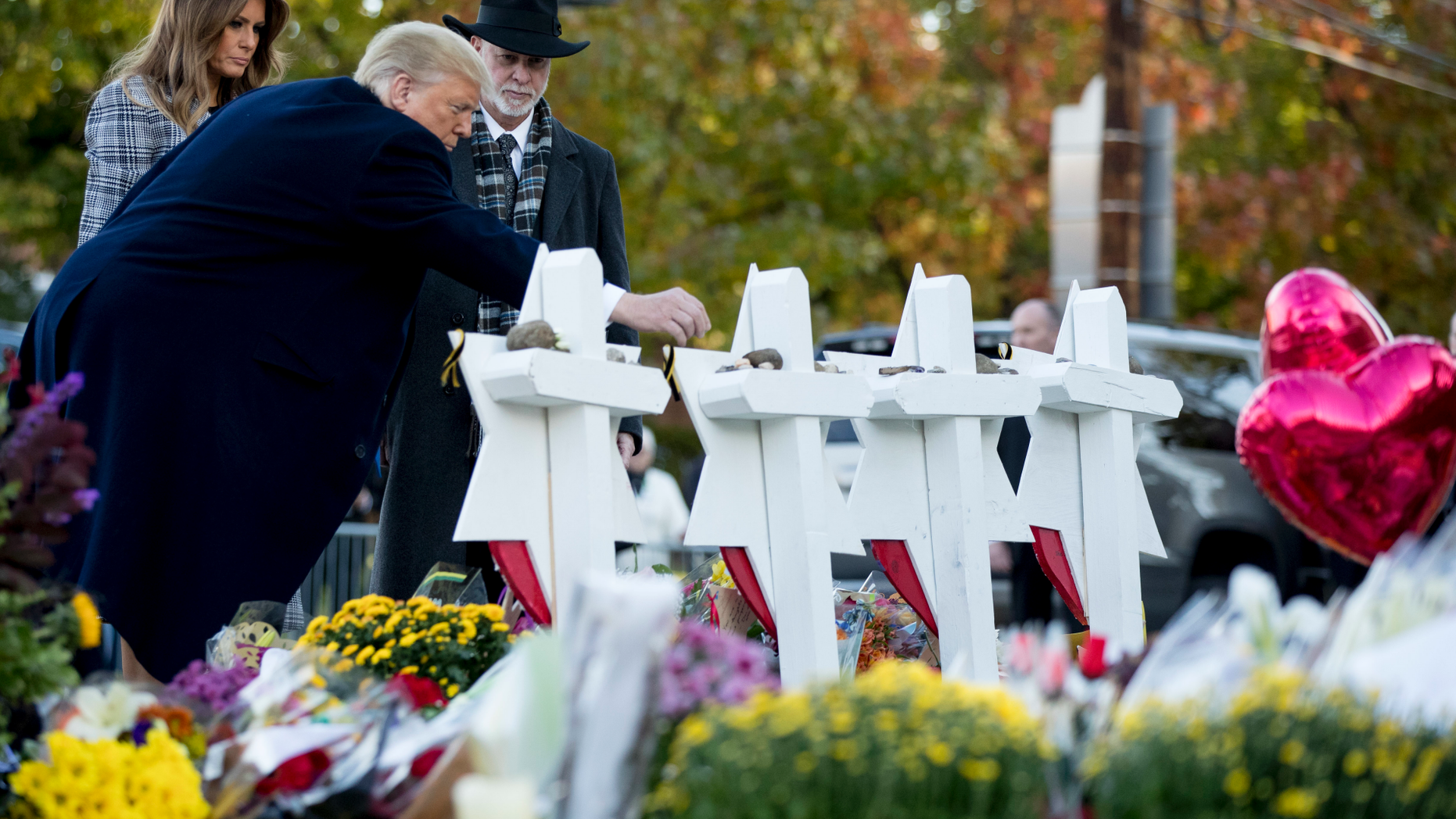 President Donald Trump, accompanied by first lady Melania Trump, left, and Tree of Life Rabbi Jeffrey Myers, right, places a stone from the White House at a memorial for those killed at the Tree of Life Synagogue in Pittsburgh, Tuesday, Oct. 30, 2018. (AP Photo/Andrew Harnik)