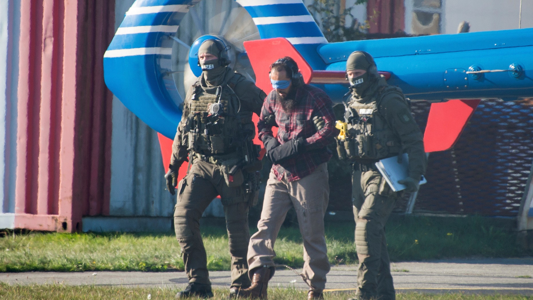 Mounir el-Motassadeq is being guided from one helicopter to the next at the airport in Hamburg.