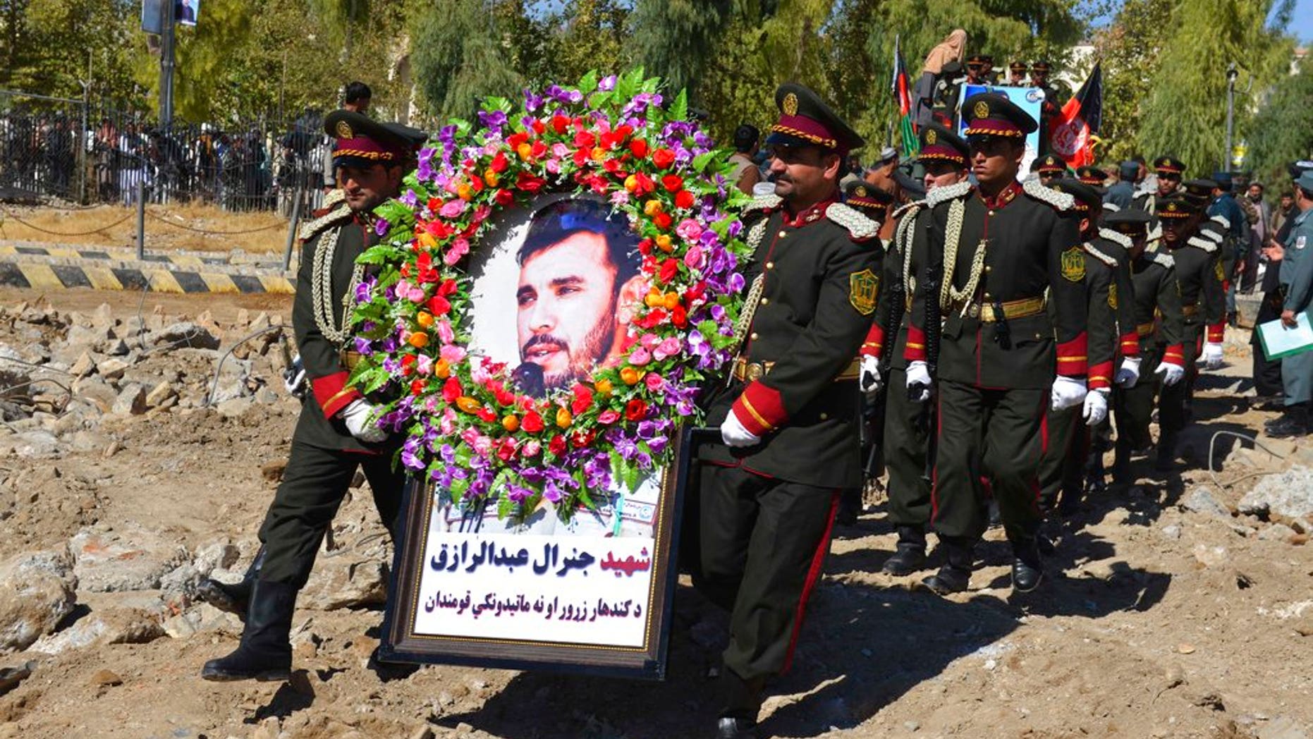 Guards of honor carry a photo of Gen. Abdul Raziq, Kandahar police chief, who was killed by a guard, during his burial ceremony in Kandahar, Afghanistan, Friday, Oct. 19, 2018.