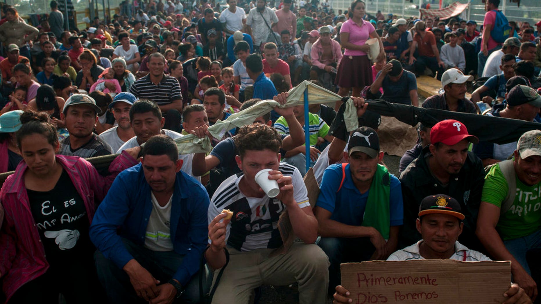 Honduras migrants wait to be attended by Mexican migration authorities on a bridge that stretches over the Suchiate River, connecting Guatemala and Mexico, in Tecun Uman, Guatemala. (AP Photo/Oliver de Ros)