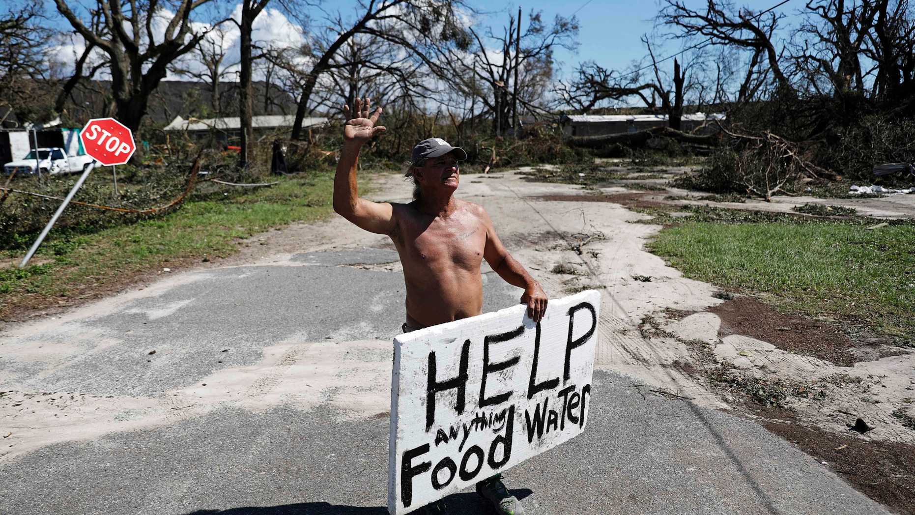 Michael Williams, 70, waves to passing motorists while looking for food and water as downed trees prevent him from driving out of his damaged home with his family in the aftermath of Hurricane Michael in Springfield, Fla., Thursday, Oct. 11, 2018. "I don't know what I'm going to," said Williams. (AP Photo/David Goldman)