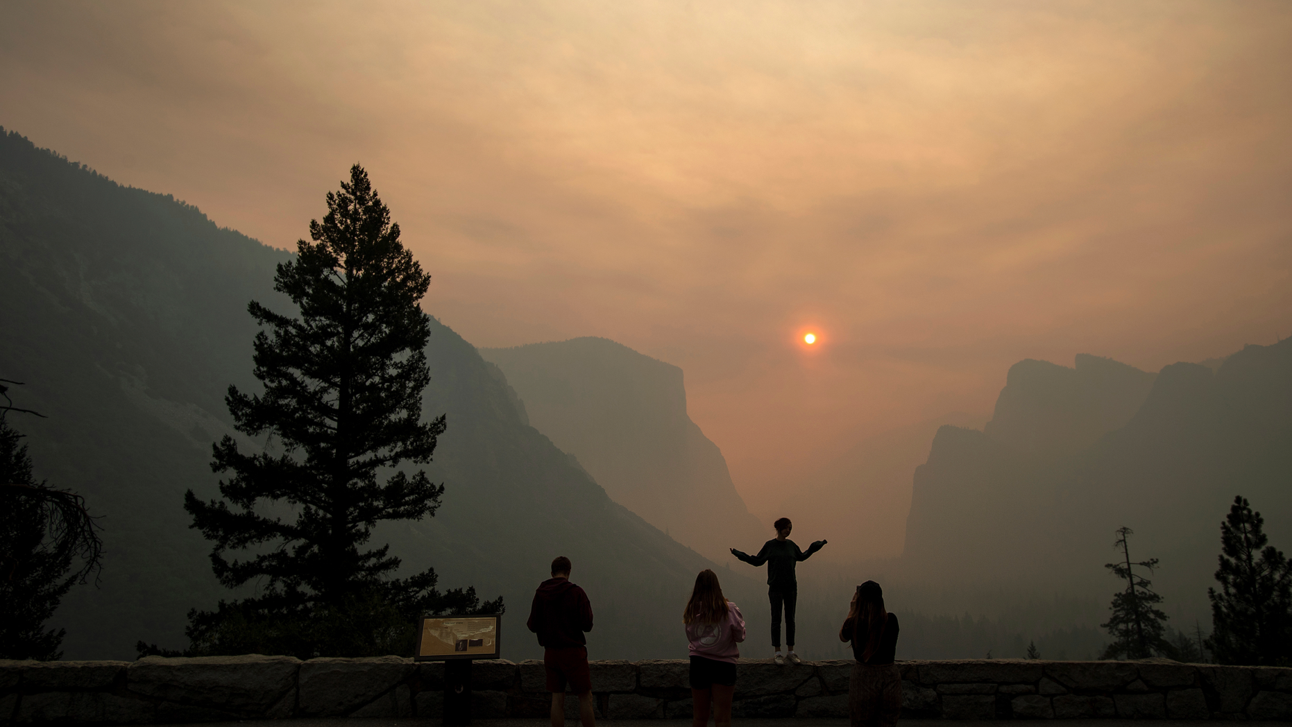 FILE - In this July 25, 2018 file photo, Hannah Whyatt poses for a friend's photo as smoke from the Ferguson fire fills Yosemite Valley in Yosemite National Park, Calif. Authorities say the Ferguson fire, that killed two firefighters and destroyed nearly a dozen buildings in Northern California, was caused by a vehicle. The U.S. Forest Service on Friday, Oct. 5, 2018, said investigators determined that a hot catalytic converter ignited dry roadside vegetation. However, investigators haven't identified the vehicle. (AP Photo/Noah Berger, File)