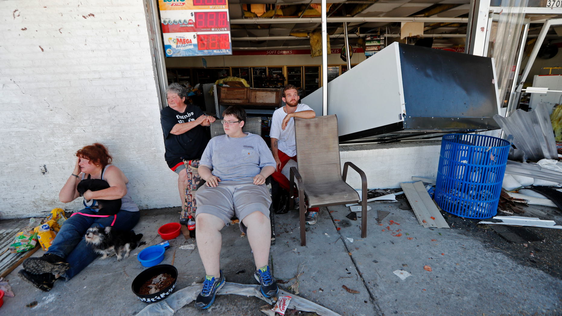 Dawn Vickers, left, her mother Patsy Vickers, son Ryder Vickers, and friend Robert Brock, right, who rode out Hurricane Michael in their now-destroyed home, sit in front of a damaged convenience store with nowhere to go, in Michael's aftermath, in Mexico Beach, Fla., Thursday, Oct. 11, 2018. Their house floated away from its foundation in the storm and they escaped the water by wading through a window. (AP Photo/Gerald Herbert)