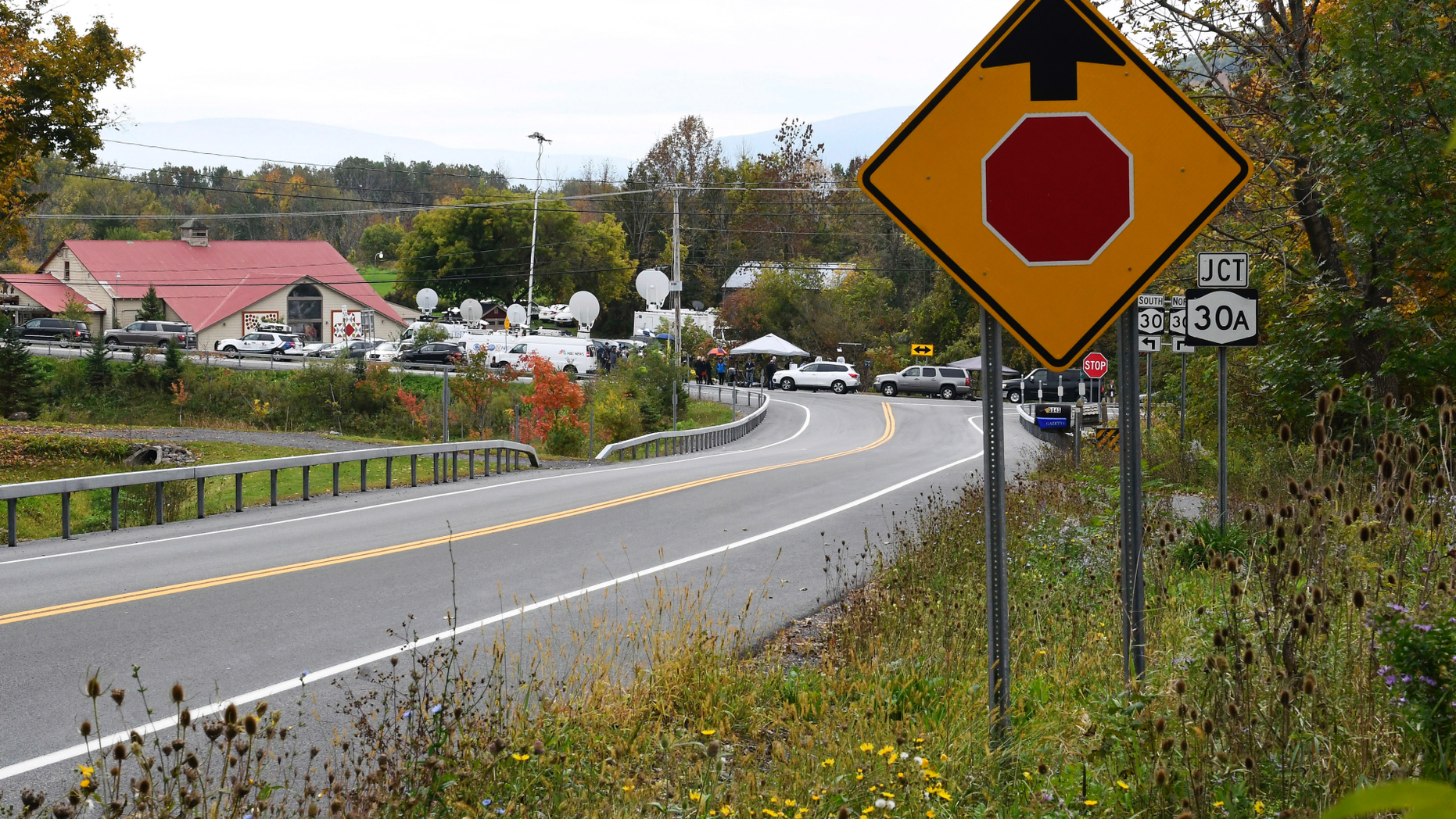 Television networks broadcast at the roadside memorial scene of Saturday's fatal limousine crash in Schoharie, N.Y., Monday, Oct. 8, 2018. A limousine loaded with people headed to a birthday party blew the stop sign at the end of a highway and slammed into an SUV parked outside a store, killing all people in the limo and a few pedestrians, officials and relatives of the victims said. (AP Photo/Hans Pennink)