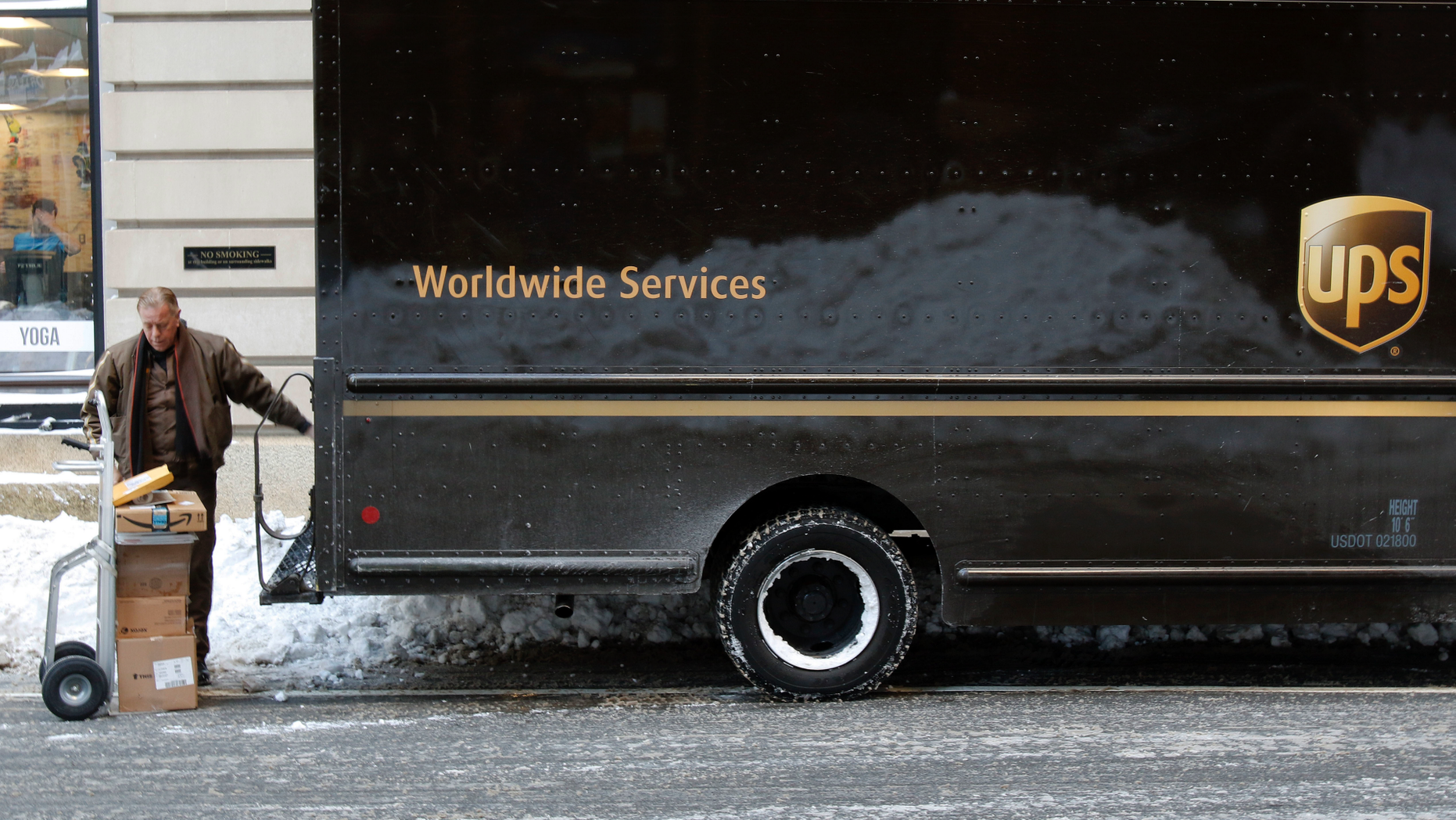 FILE- In this Jan. 5, 2018, photo, a UPS delivery driver loads his cart with packages from his truck, in Boston. UPS Inc. reports earnings Wednesday, Oct. 24. (AP Photo/Bill Sikes, File)