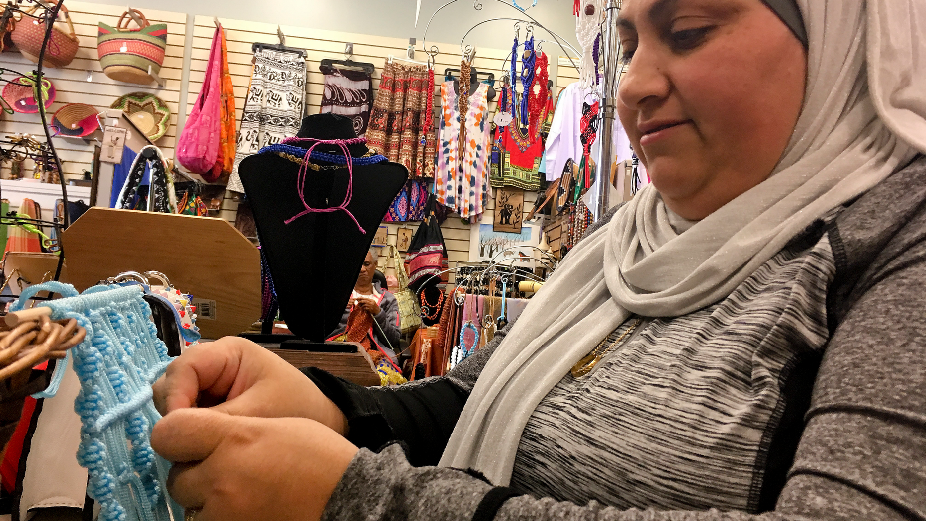Former Iraqi refugee Nadeen Yousef creates hand crafts to sell at the West Side Bazaar, where refugees sell clothes, crafts and food, on Friday, Sept. 28, 2018, in Buffalo, N.Y. Thousands of refugees have settled in Buffalo in recent years even as others have left the city. Some locals worry that the Trump administration's policies reducing the numbers of new arrivals will harm the city's economy. (AP Photo/ Michael Hill)
