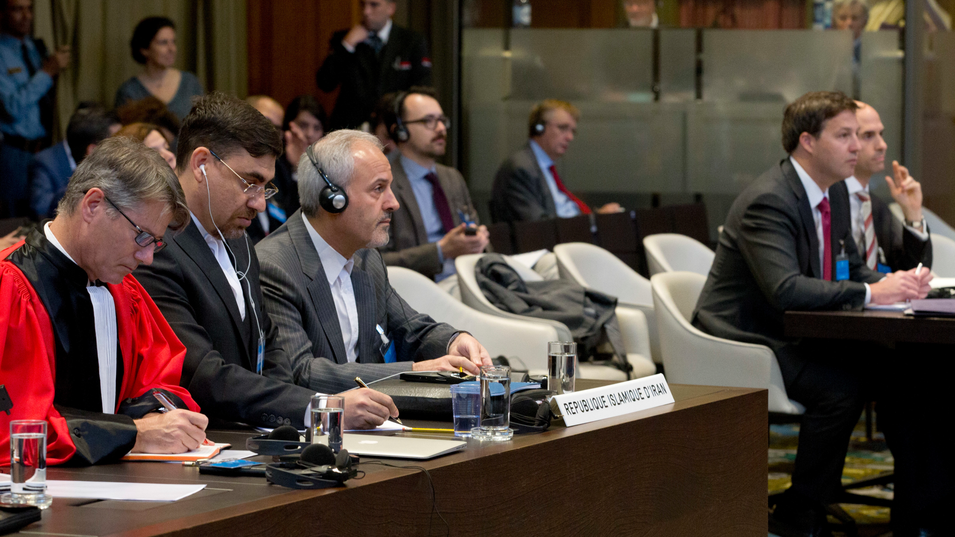 In this Wednesday Oct. 3, 2018, image Mohammed Zahedin Labbaf, third left, agent for the Islamic Republic of Iran, and the U.S. delegation, right, listen to the ruling of the judges on an Iranian request to order Washington to suspend sanctions against Tehran, at the International Court of Justice, or World Court, in The Hague, Netherlands. The U.S. is urging the United Nations' highest court Monday Oct. 8, 2018, to toss out a case filed by Iran that seeks to recover around $2 billion worth of frozen assets the U.S. Supreme Court awarded to victims of a 1983 bombing in Lebanon and other attacks linked to Iran.(AP Photo/Peter Dejong)