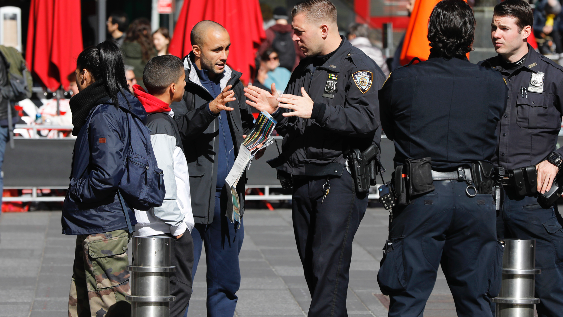 A New York City Police Department officer assists a person in New York's Times Square, Friday, Oct. 19, 2018. New reforms aimed at improving police interactions in New York City include requirements that officers hand out their business cards to people they stop and explain why law enforcement activity is taking place. (AP Photo/Richard Drew)