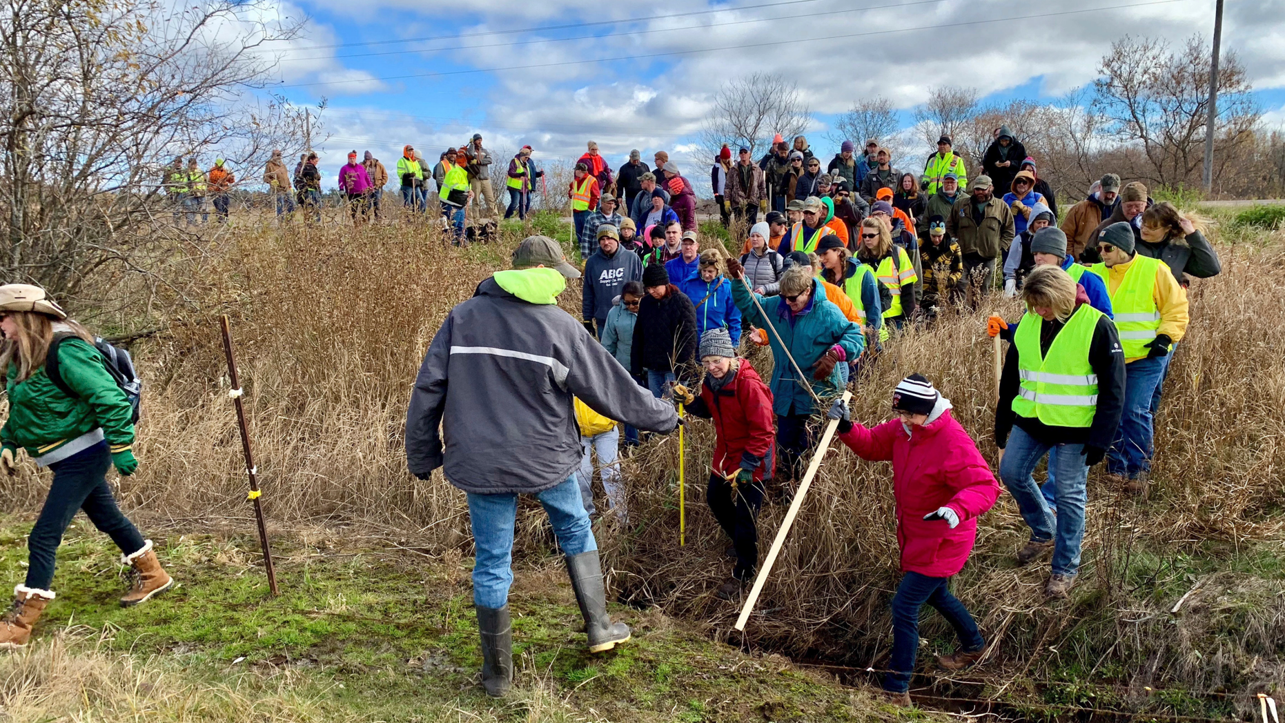 Volunteers cross a creek and barbed wire near Barron, Wis., Tuesday, Oct. 23, 2018, on their way to a ground search for 13-year-old Jayme Closs who was discovered missing Oct. 15 after her parents were found fatally shot at their home. The search for Closs was expanded Tuesday, with as many as 2,000 volunteers expected to take part in a search of the area. (AP Photo/Jeff Baenen)