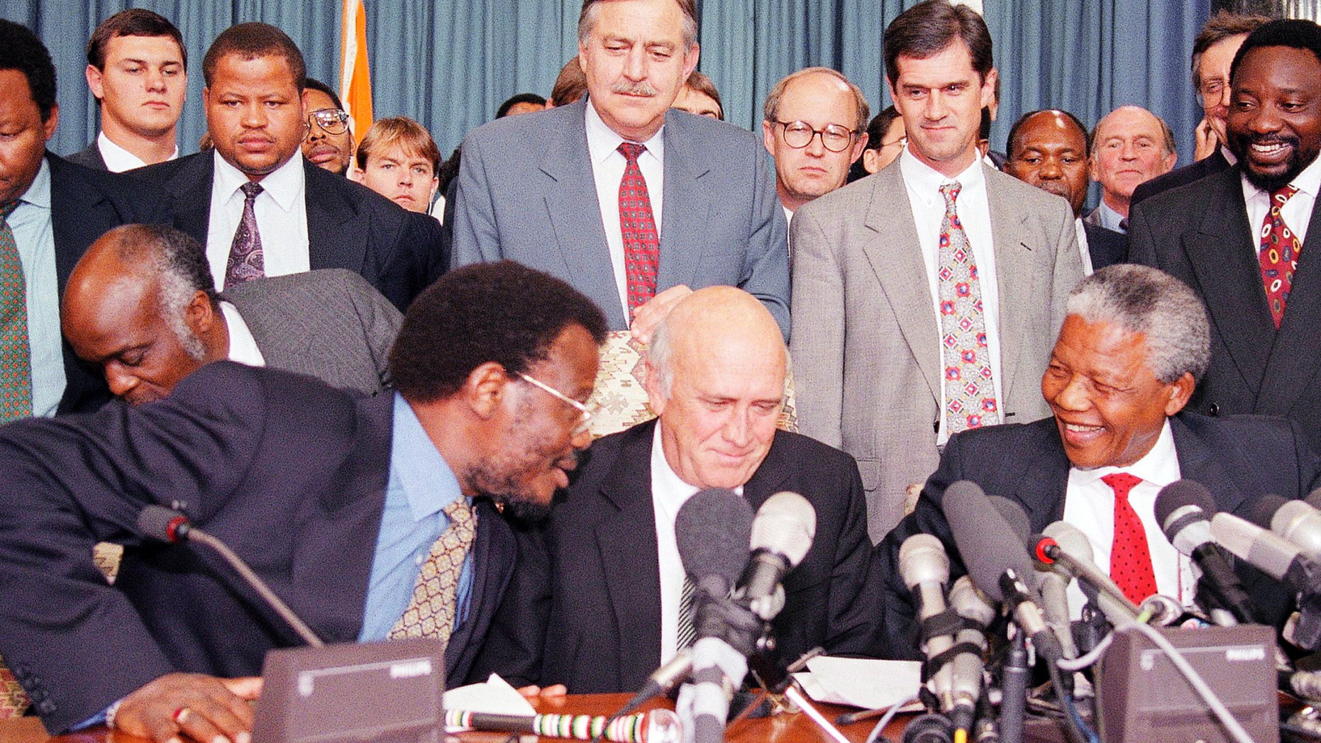 FILE - This April 19, 1994 file photo shows in the front row; Inkatha Freedom Party (IFP) Chief Mangosuthu Buthelezi, left, President F.W. de Klerk, middle, and African National Congress (ANC) President Nelson Mandela, right, exchanging words at a news conference, while in the back row at center South African Foreign Minister Pik Botha looks over them, in Pretoria, South Africa. Botha, the last foreign minister of South Africa's apartheid era and a contradictory figure who staunchly defended white minority rule but eventually recognized that change was inevitable, died on Friday, Oct. 12, 2018 at age 86. Next to Botha, second from right is Roelf Meyer, chief government negotiator, and ANC's Secretary General Cyril Ramaphosa, right. (AP Photo/Lynne Sladky, File)