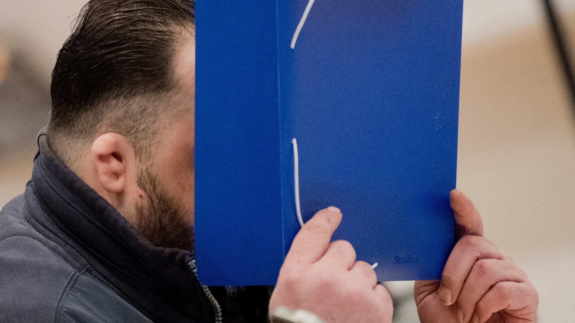 Niels Hoegel covers his face with a folder as he arrives at the Oldenburg district court at the Weser Ems halls in Oldenburg, Germany, Tuesday, Oct. 30
