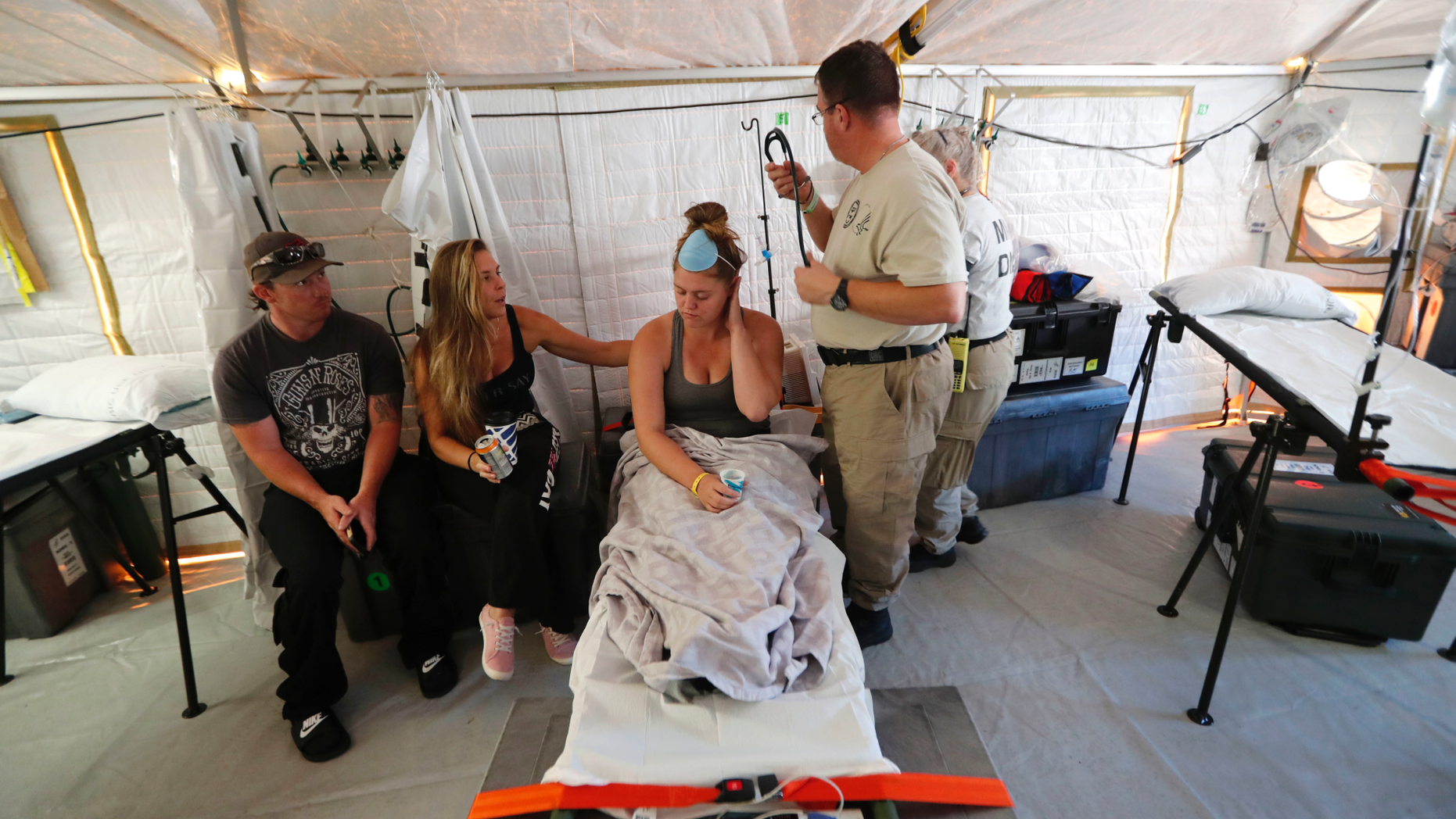 Aleeah Racette receives medical treatment inside the Florida 5 Disaster Medical Assistance Team tent, outside the Bay Medical Sacred Heart hospital, in the aftermath of Hurricane Michael in Mexico Beach, Fla., Thursday, Oct. 18, 2018. At left is her mother, Amy Cross, and Amy's fiance, Corey Shuman. (AP Photo/Gerald Herbert)