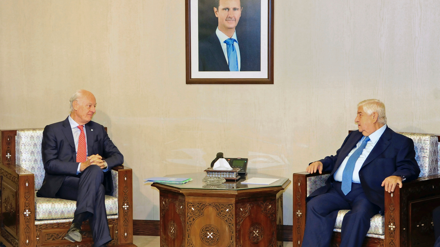 In this photo released by the Syrian official news agency SANA, Syria's Foreign Minister Walid al-Moallem, right, meets with U.N. Special Envoy for Syria Staffan de Mistura, in Damascus, Syria, Wednesday, Oct. 24, 2018. Syrian state media said al-Moallem has told the U.N. envoy that the constitution is a "sovereign" matter and Damascus will not allow any foreign intervention regarding it. (SANA via AP)