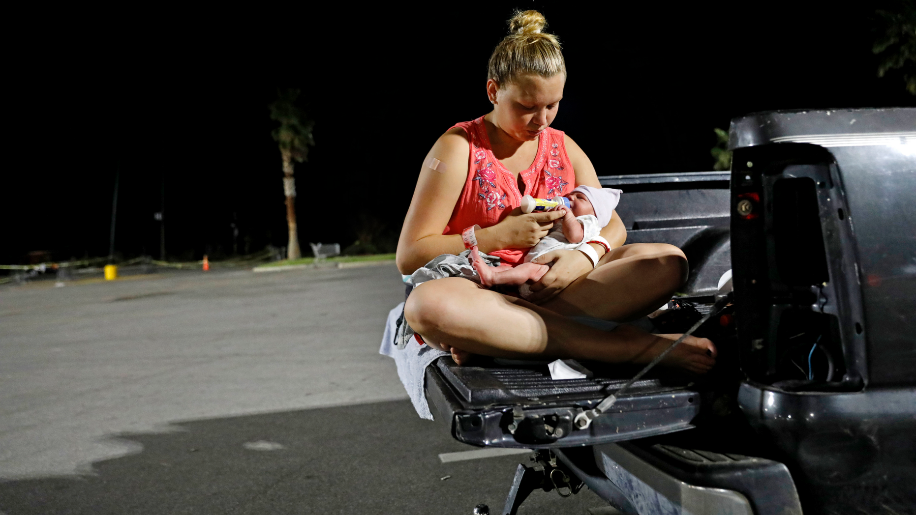 Lorrainda Smith, feeds her two-day-old son Luke out of the back of her pickup truck while preparing to spend the first night out of the hospital with her newborn and husband Wilmer Capps in a parking lot in Panama City, Fla., Monday, Oct. 15, 2018, as their home was badly damaged from Hurricane Michael. "One day we had it all, the next we had nothing," added Smith. "This is not what I thought I'd be bringing him back to." (AP Photo/David Goldman)