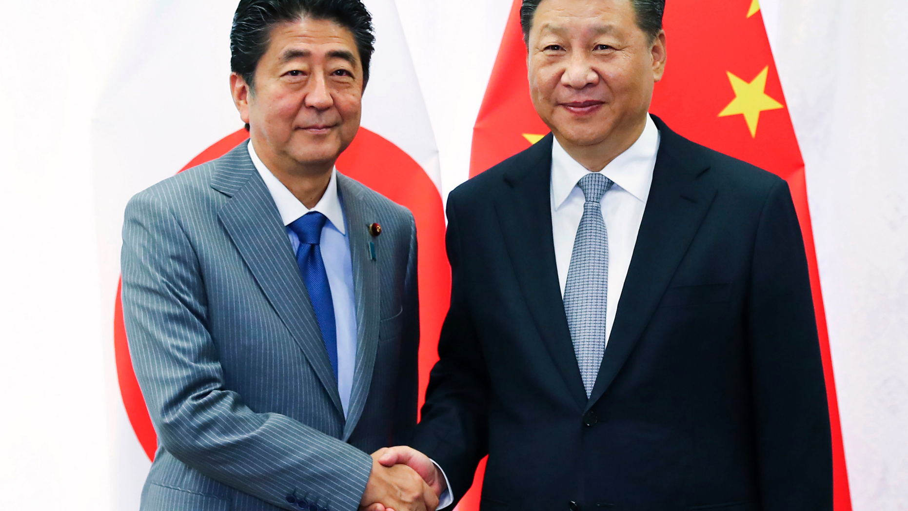 FILE - In this Sept. 12, 2018, file photo released by China's Xinhua News Agency, Chinese President Xi Jinping, right, shakes hands with Japanese Prime Minister Shinzo Abe during a meeting on the sidelines of the Eastern Economic Forum in Vladivostok, Russia. Abe is to travel to China later in October, 2018 for his first formal visit in seven years, in a further sign of improving relations between the regional rivals. (Xie Huanchi/Xinhua via AP, File)